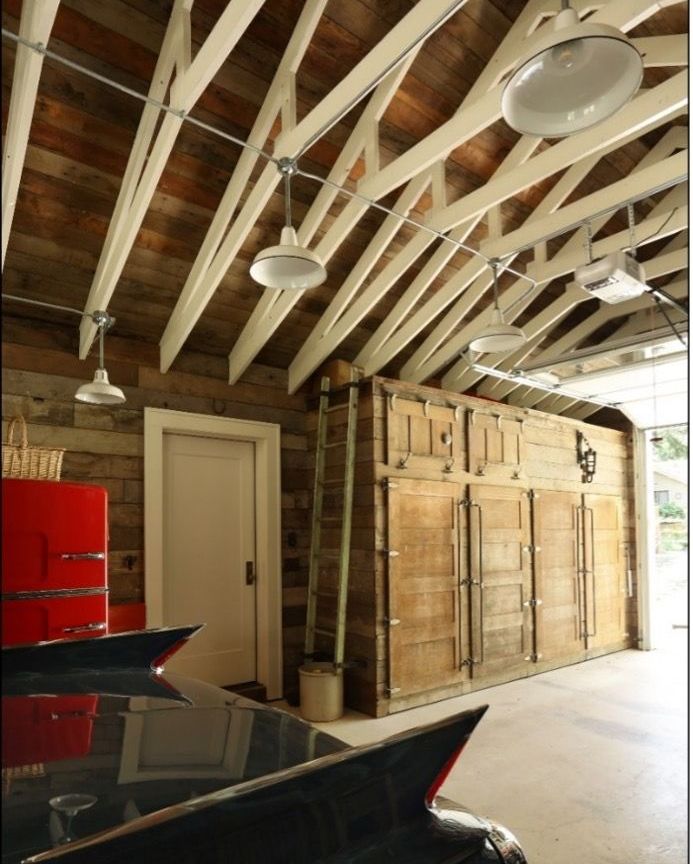 A black car is parked in a garage with a red refrigerator