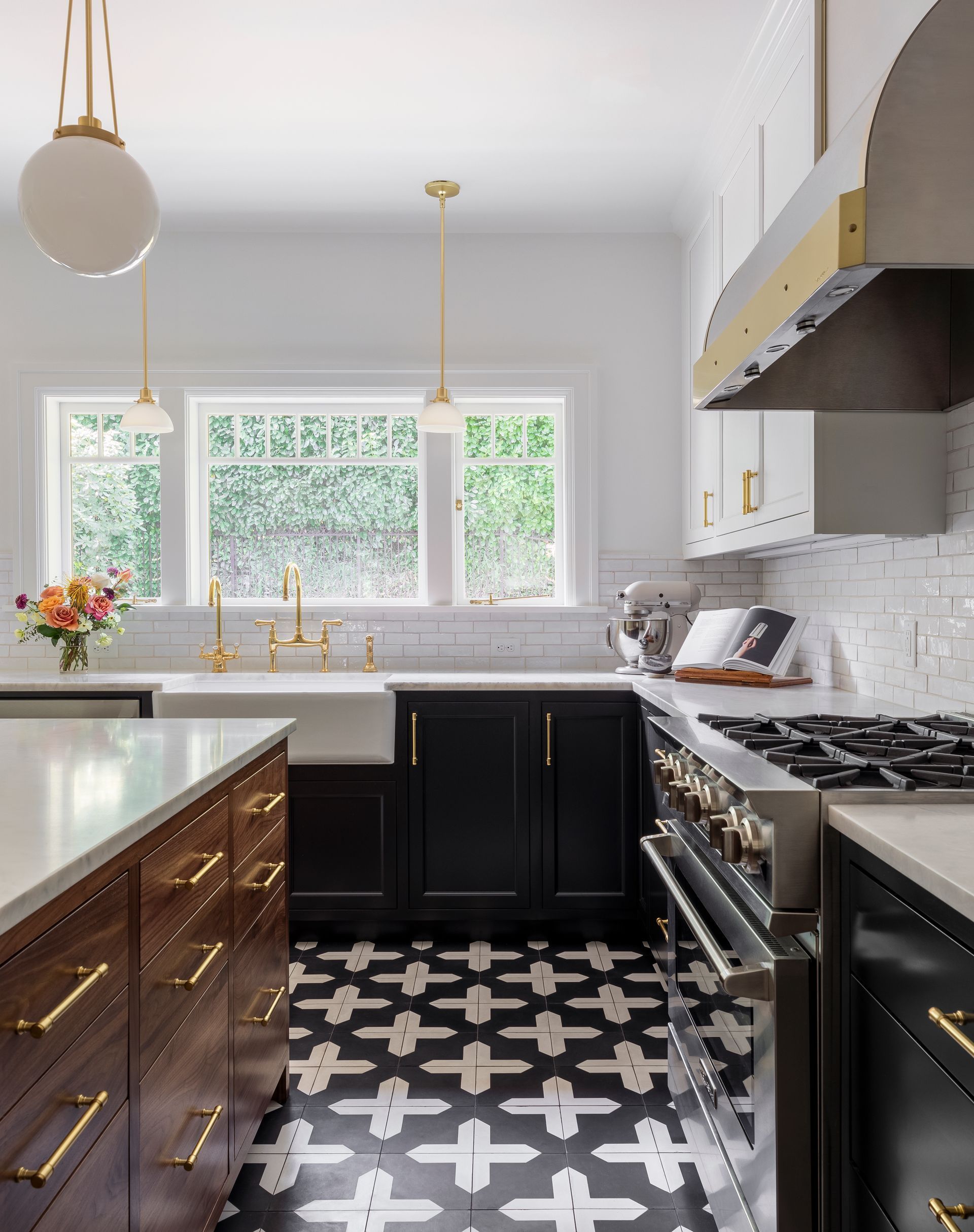 White upper cabinets and blackened lowers with a stained walnut island harmonize on a black and white patterned tile floor.