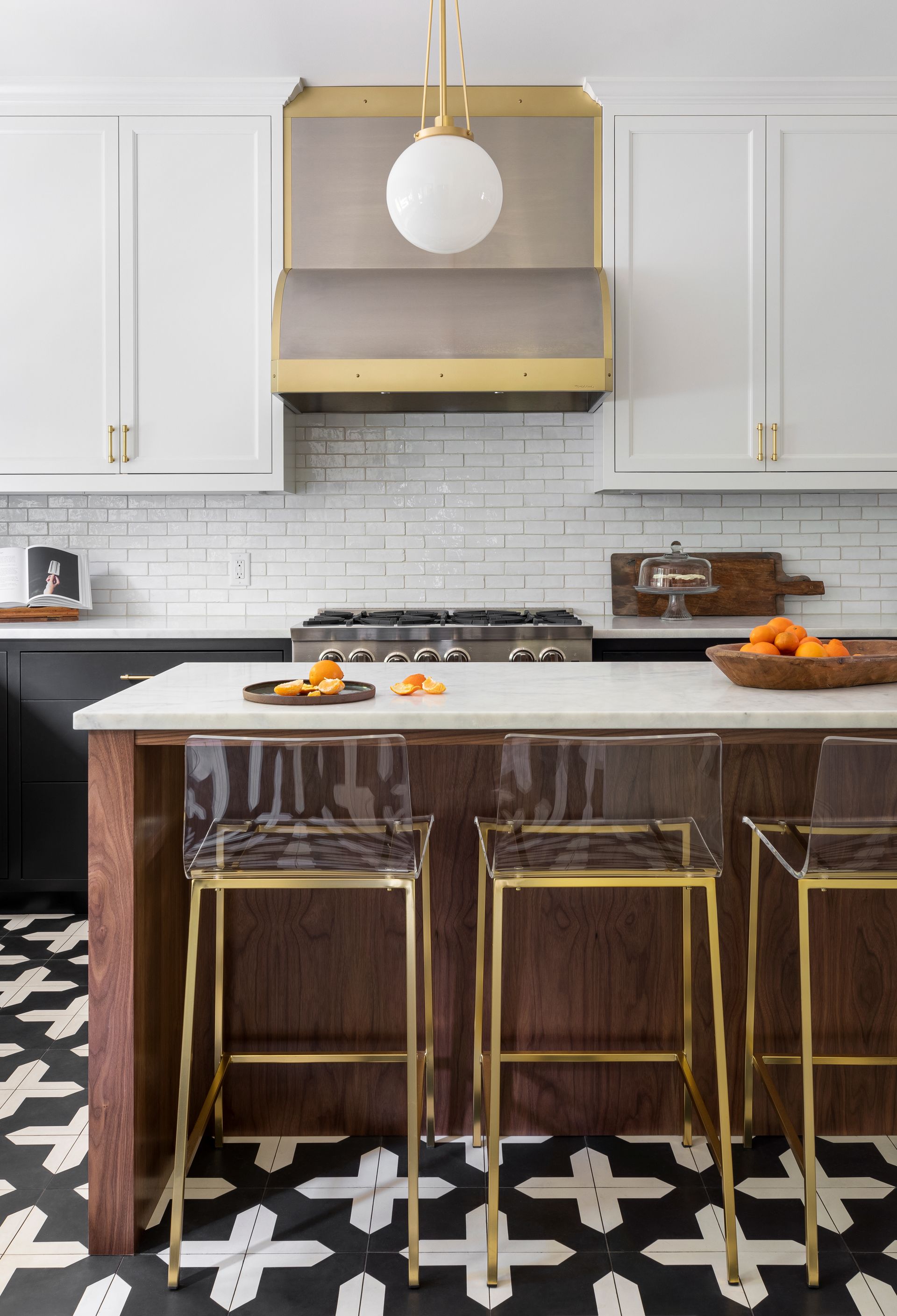 White upper cabinets and blackened lowers with a stained walnut island harmonize on a black and white patterned tile floor.