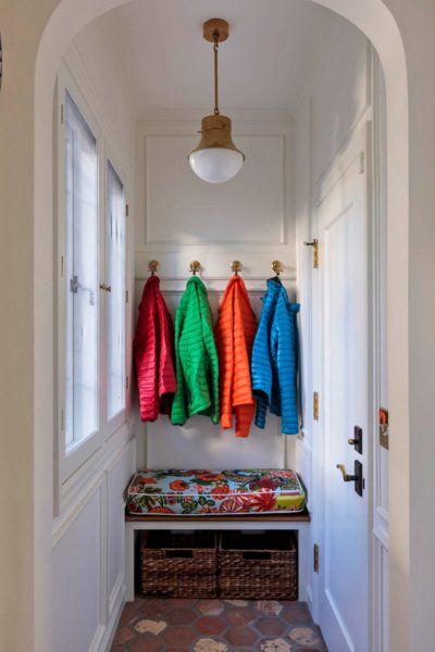 A hallway with jackets hanging on hooks and a bench.