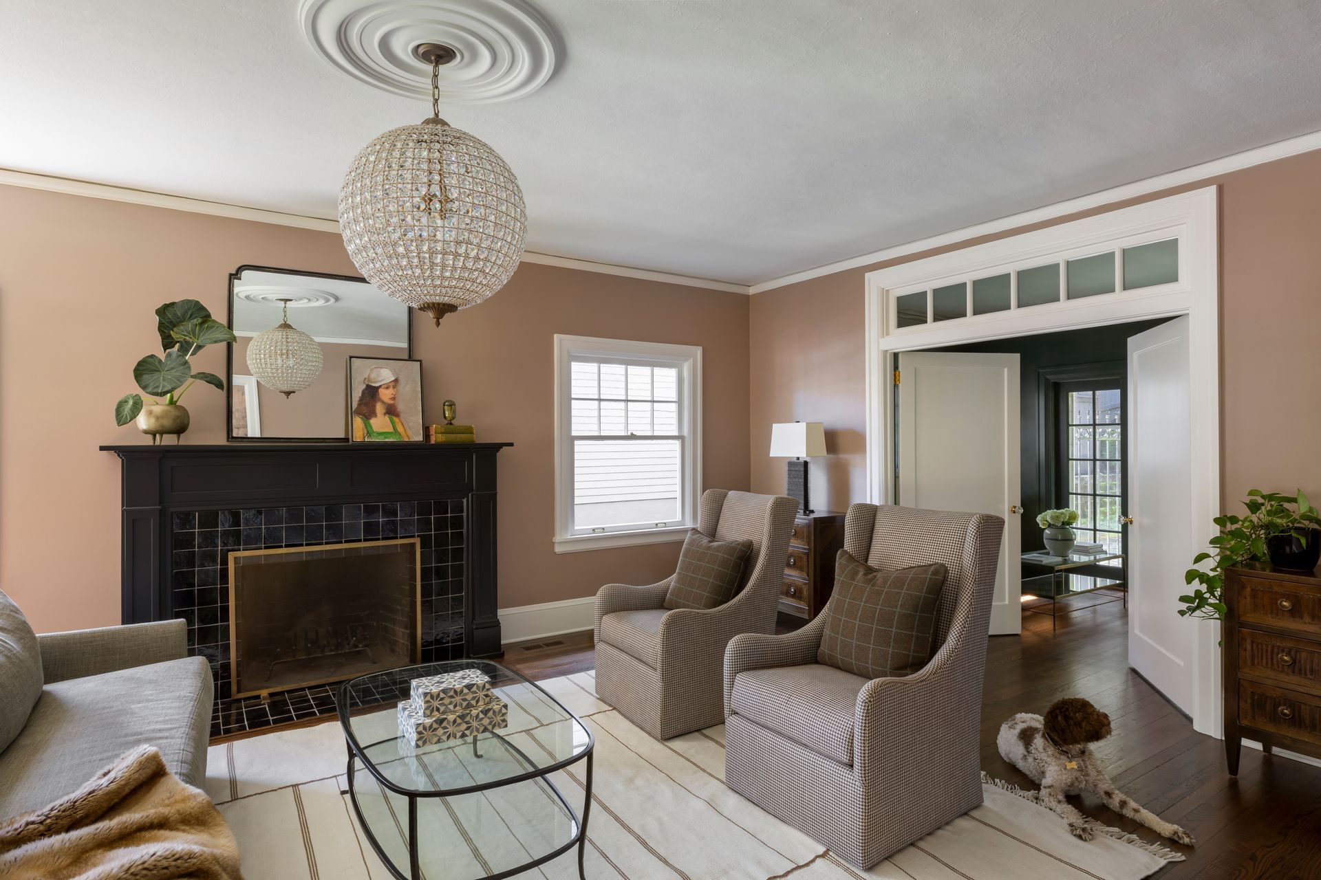 New doors with a transom window connect a serene, dusty pink living room with the parlor.