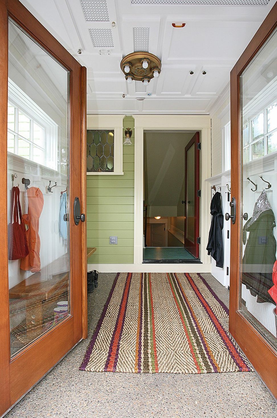 Looking into the mudroom with salvaged cabinet doors on the ceiling, and reclaimed windows, columns and lighting all adding charm