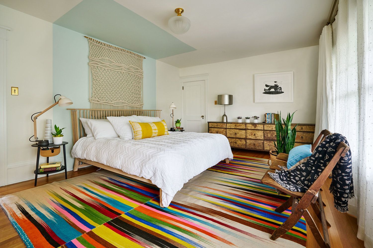 The main bedroom has treetop views through original windows and soft, colorful touches throughout.