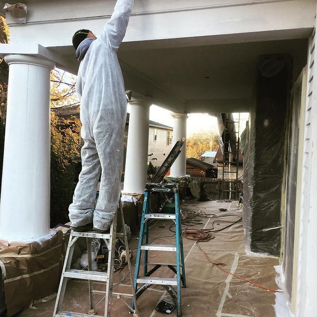A man standing on a ladder with his arm in the air