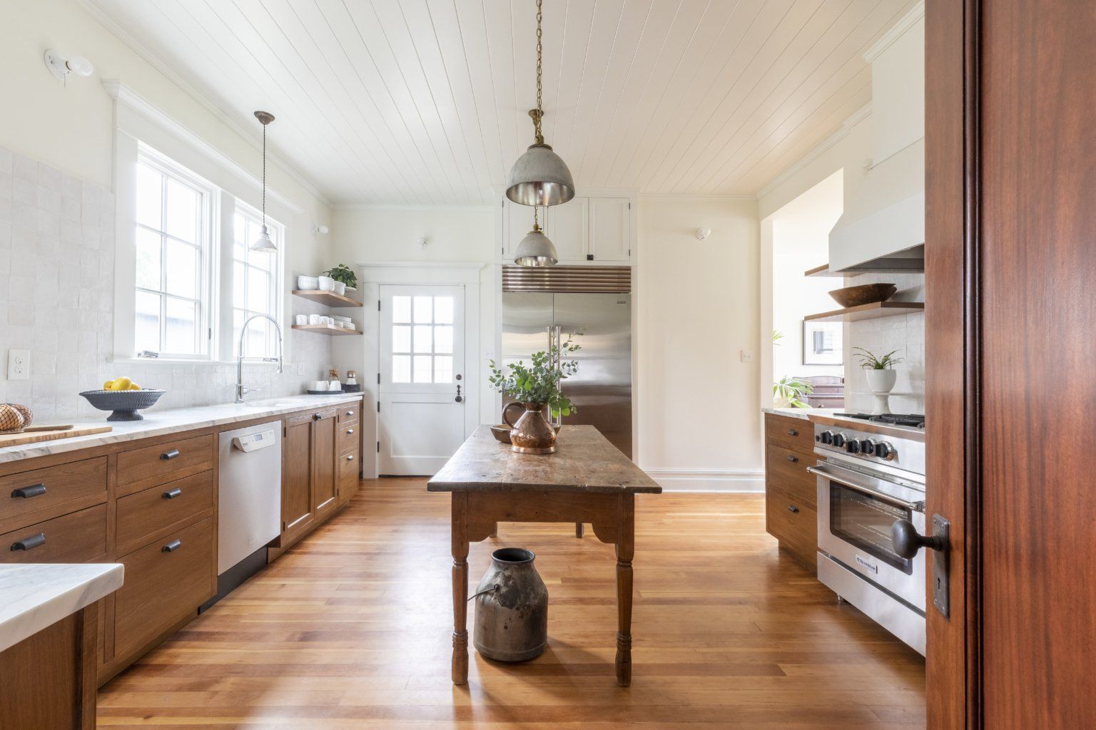 A kitchen with wooden cabinets , stainless steel appliances , and a wooden table.