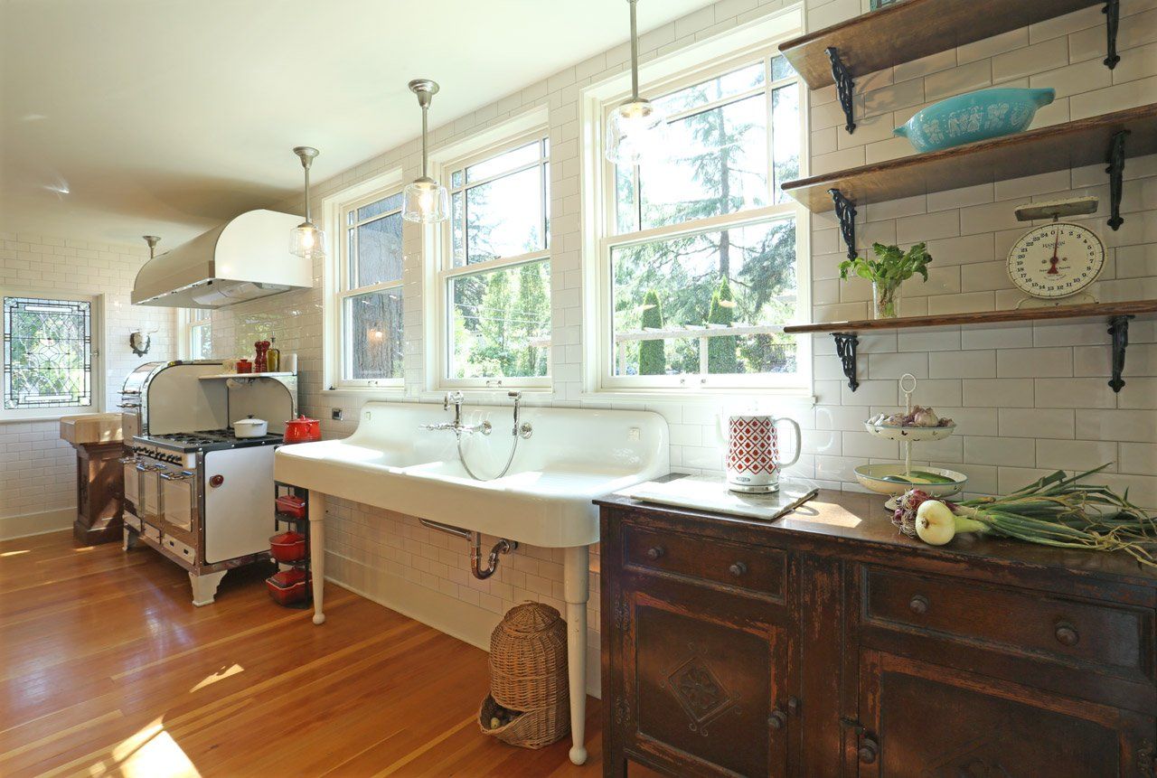 The new kitchen looks original with an antique window, range, drainboard sink on legs, salvaged furniture as cabinets and reclaimed Fir floor.
