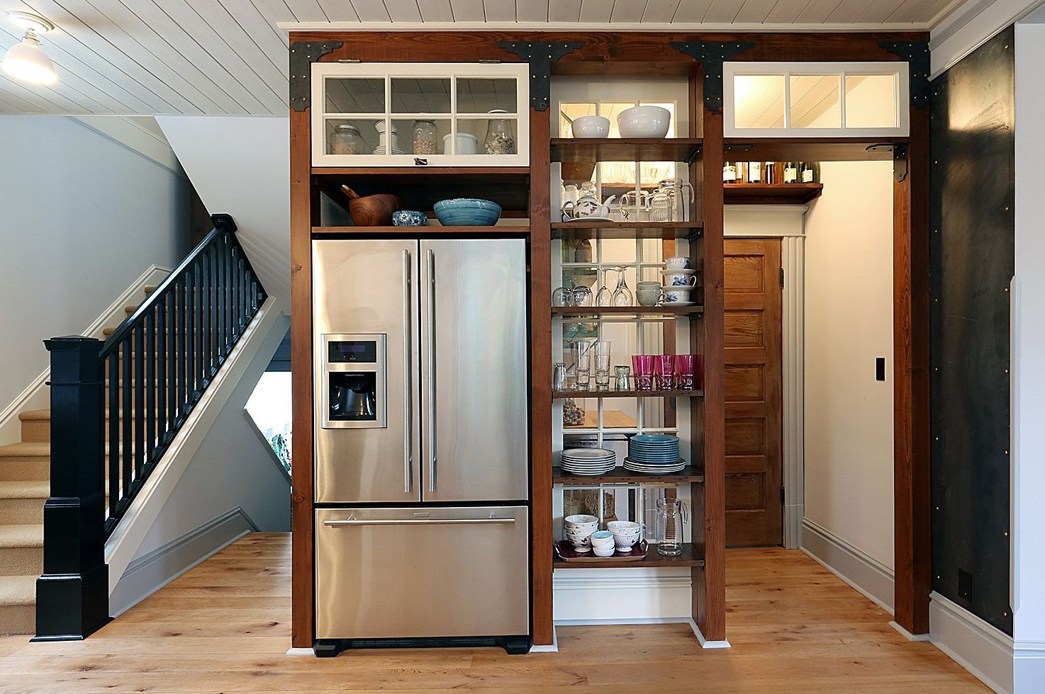 In the open kitchen, a pantry that mimics an old storefront sits behind the refrigerator and side cabinet