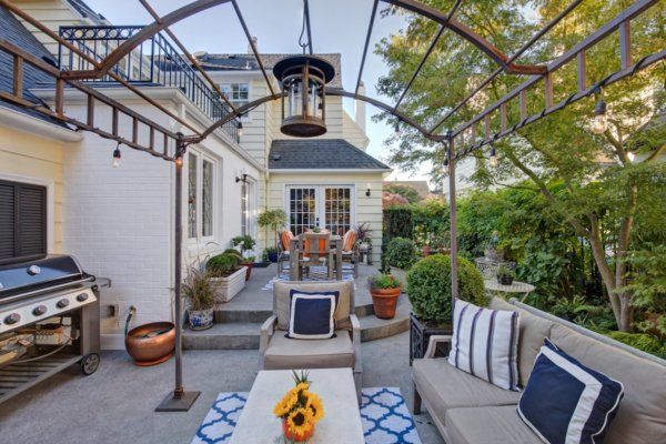 A patio with a couch , chairs , table and grill
