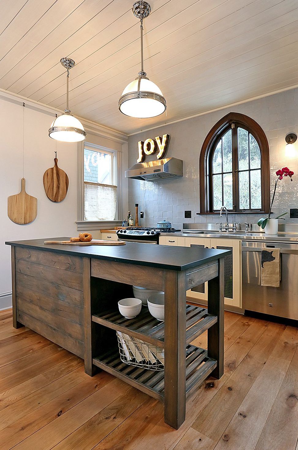 Zellige tile frames a gothic casement window in this richly textured kitchen with a custom stone-topped island in the foreground