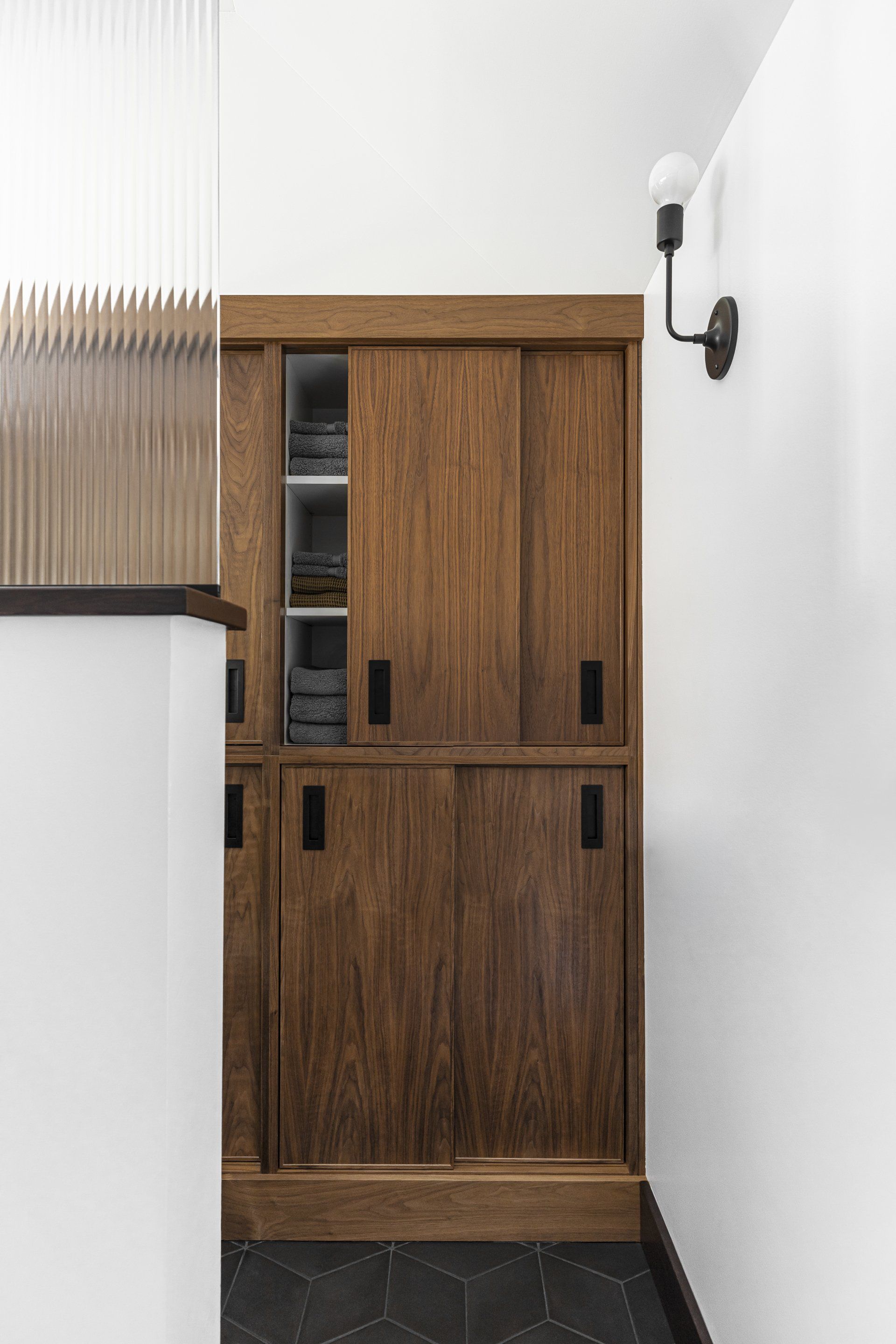 Adjacent to the WC, custom walnut cabinets slide open. 