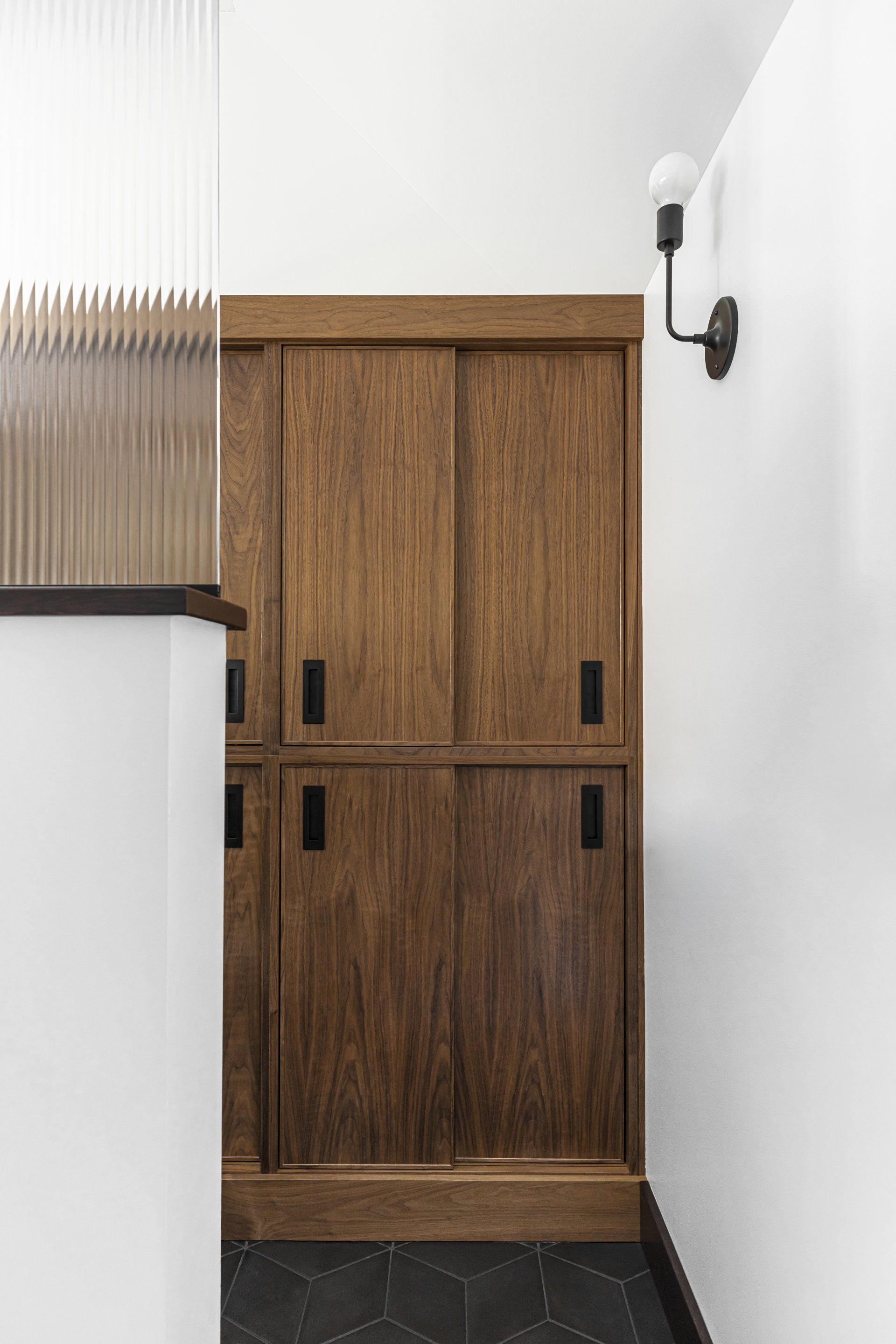 Adjacent to the WC, custom walnut cabinets slide closed.