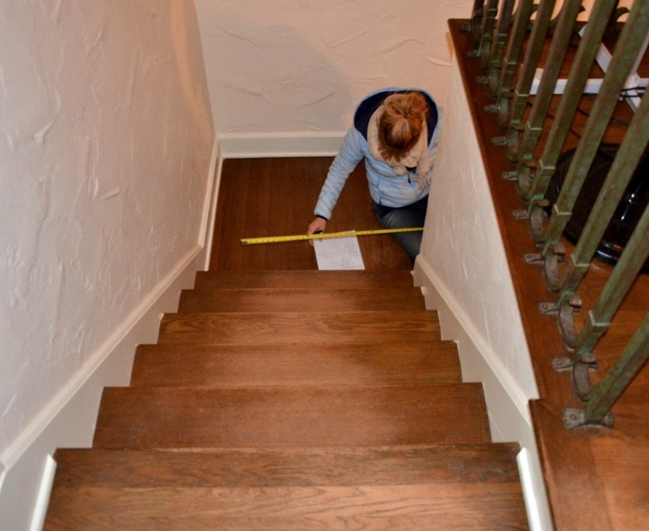 A woman is measuring the stairs with a tape measure
