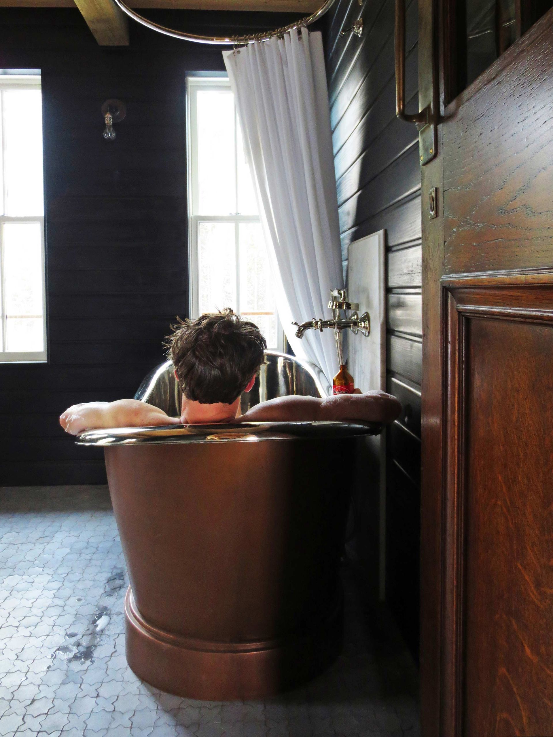 A man is sitting in a bathtub in a bathroom