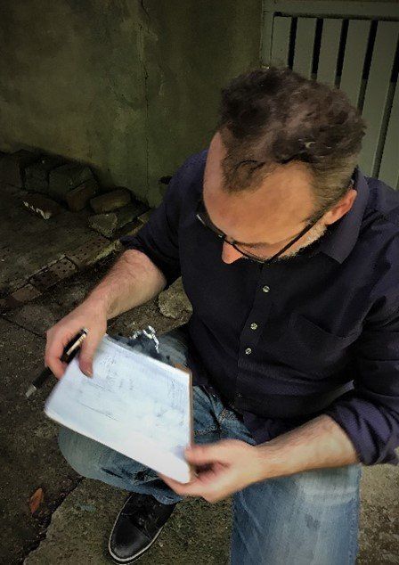 A man is sitting on the ground holding a piece of paper and a pen.