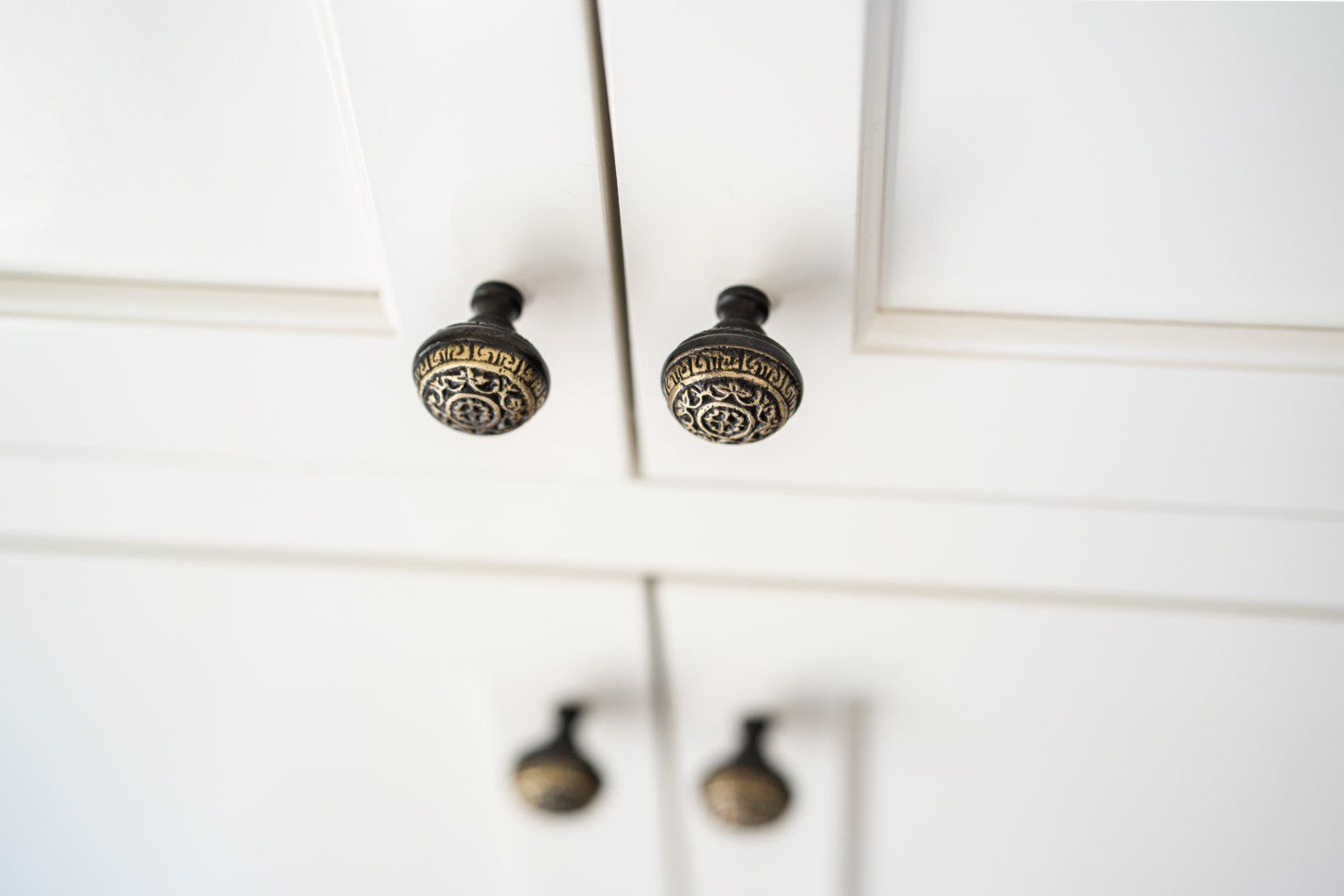 A close up of a white cabinet with black and gold handles.