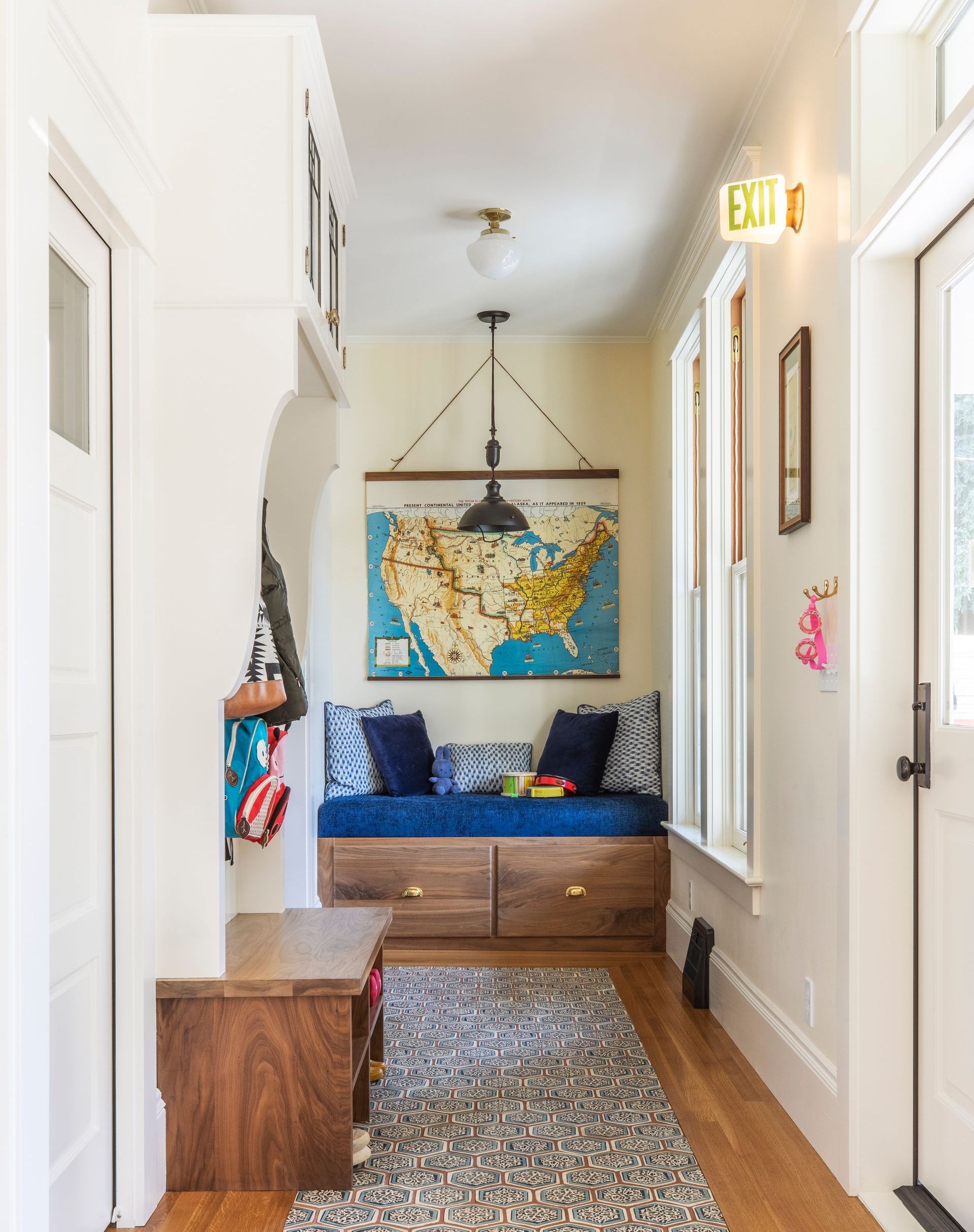 Narrow hallway with built-in blue bench and map. Mosaic floor and white walls.