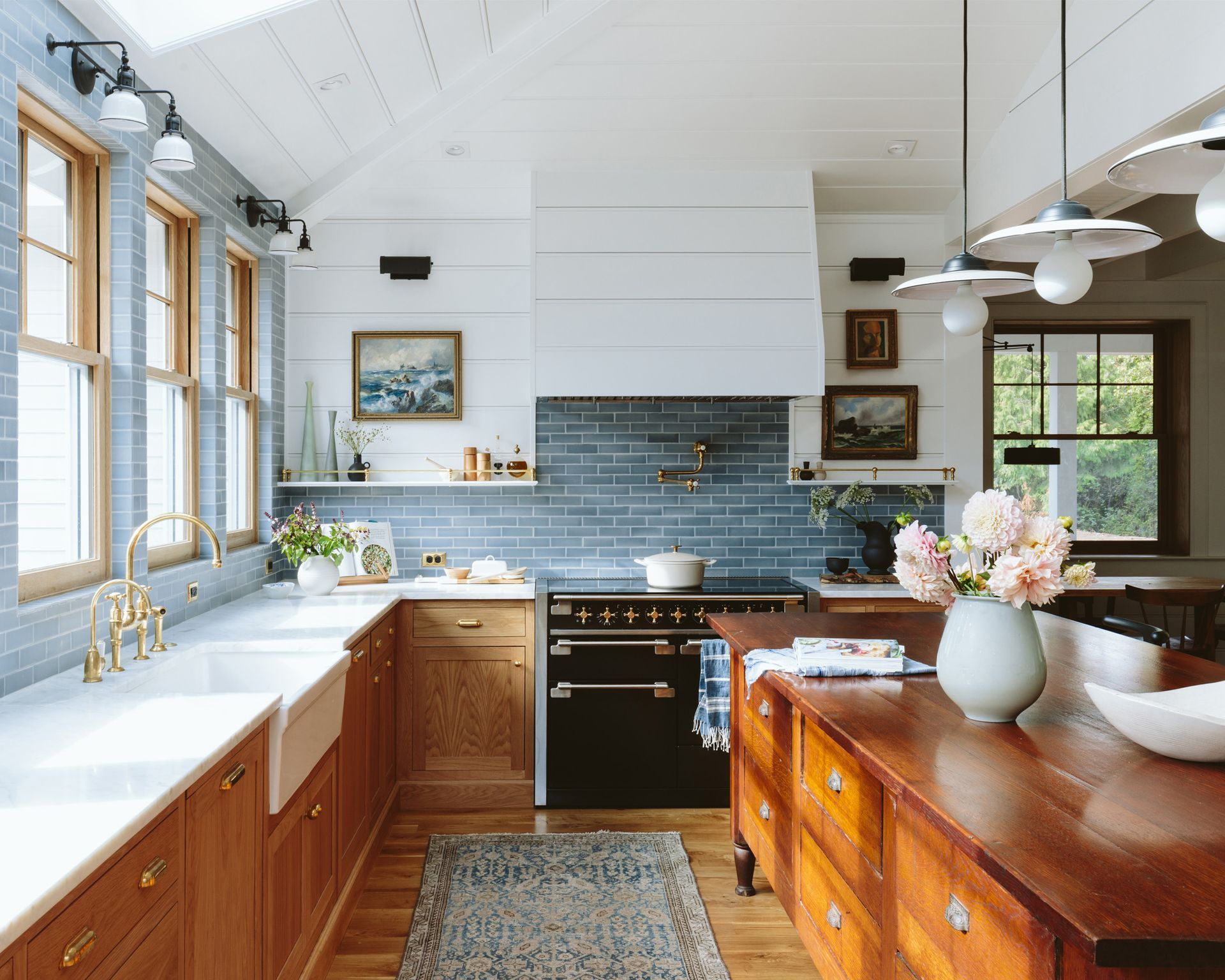 A 1910 farmhouse kitchen remodel within the 1960’s addition including custom and vintage cabinets, industrial style light fixtures, blue tile and large beadboard paneling on the walls, vaulted ceilings and the hood.