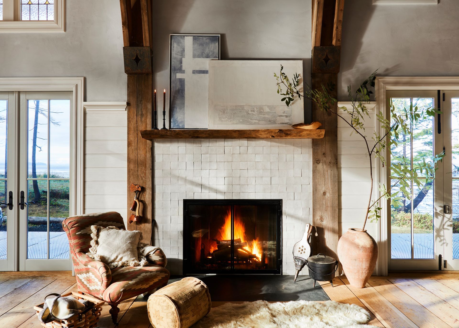 Gas fireplace with a zellige tile surround, weathered timber posts and mantel shelf, wide plank flooring and casual furnishing. 