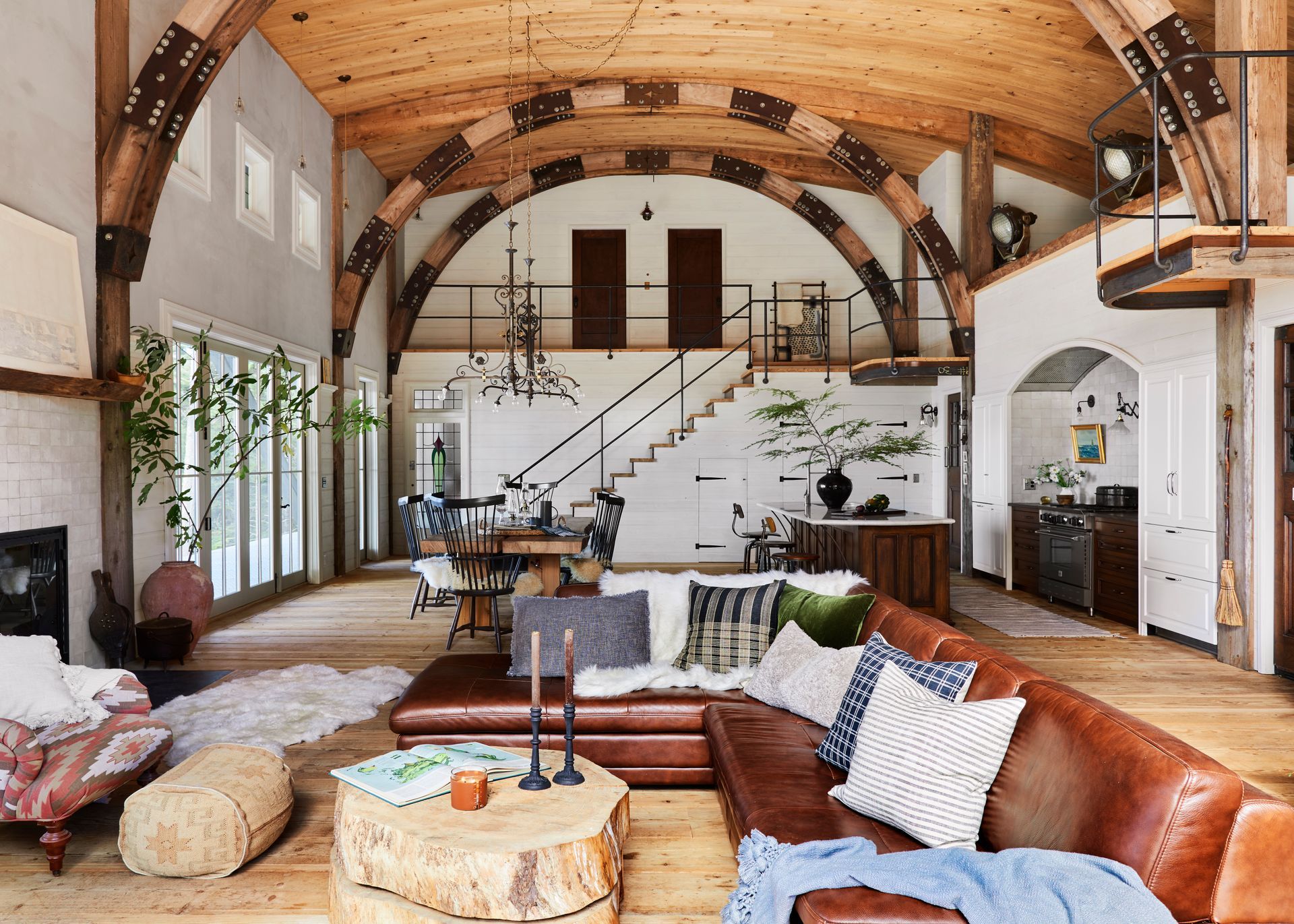 Large, open living space with arched beams and arched hood, eclectic fixtures and furnishings and rustic finishes.