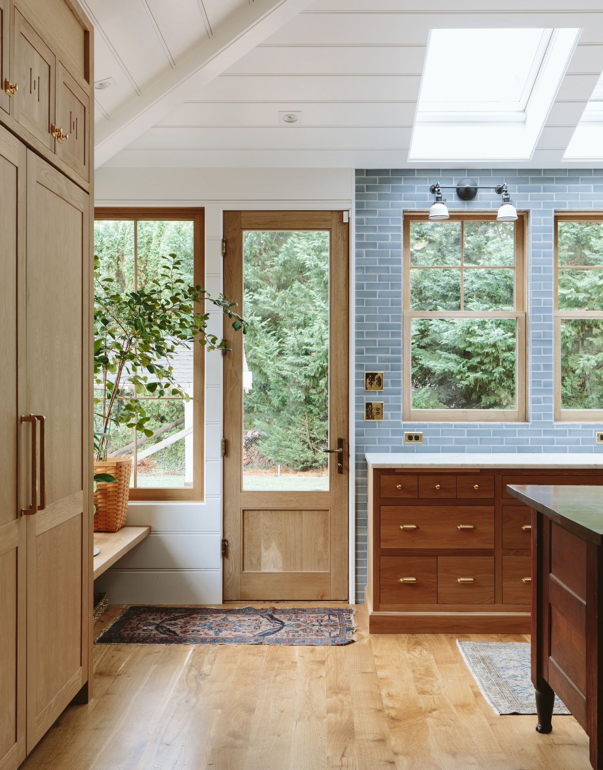 Kitchen with light wood cabinets, a glass door, and blue tiled backsplash, bright and airy.