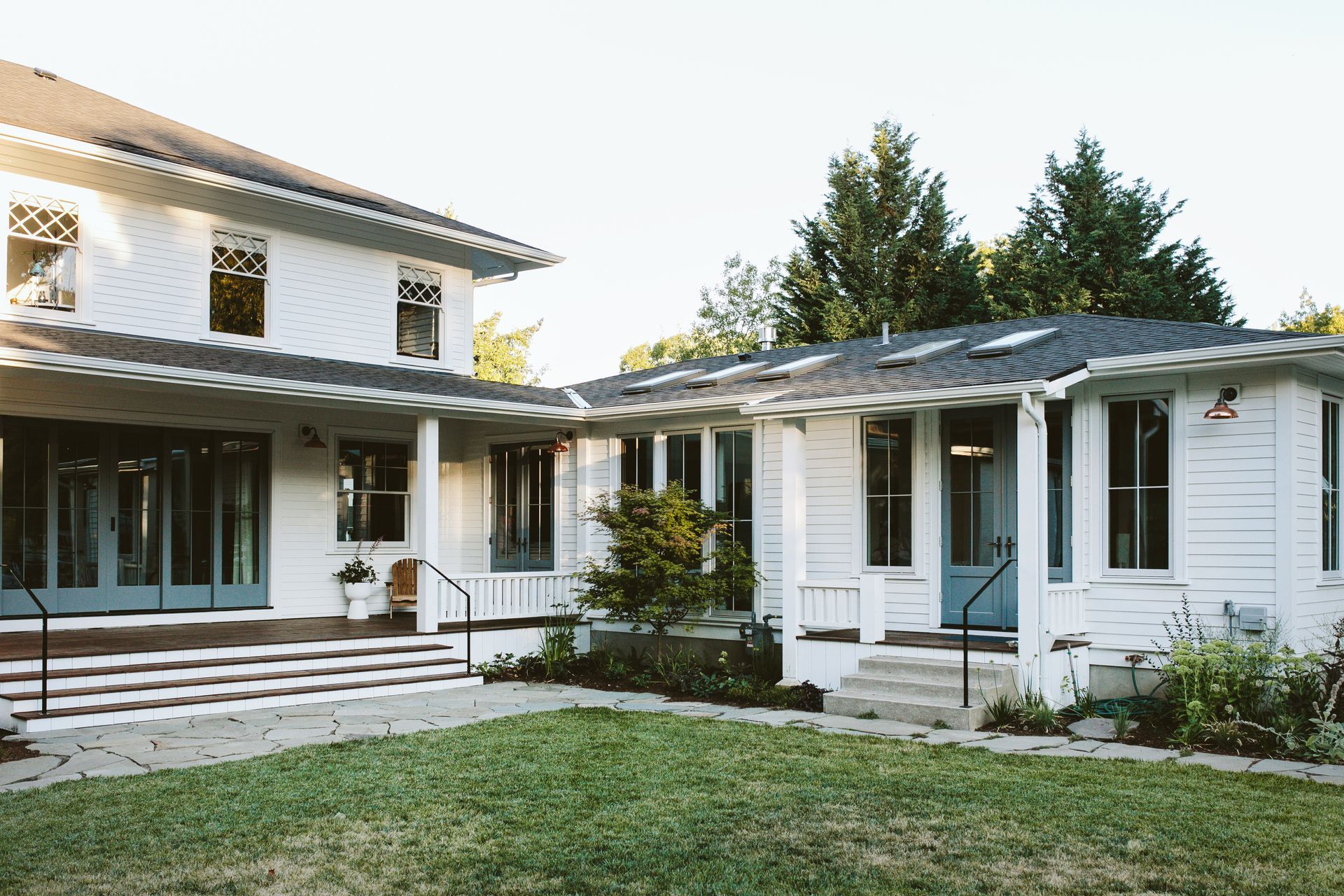 Side of a 1910 farmhouse with porch addition, large accordion door, cottage style double hung windows with diamond shaped divided lights and a remodeled addition from the 1960’s.