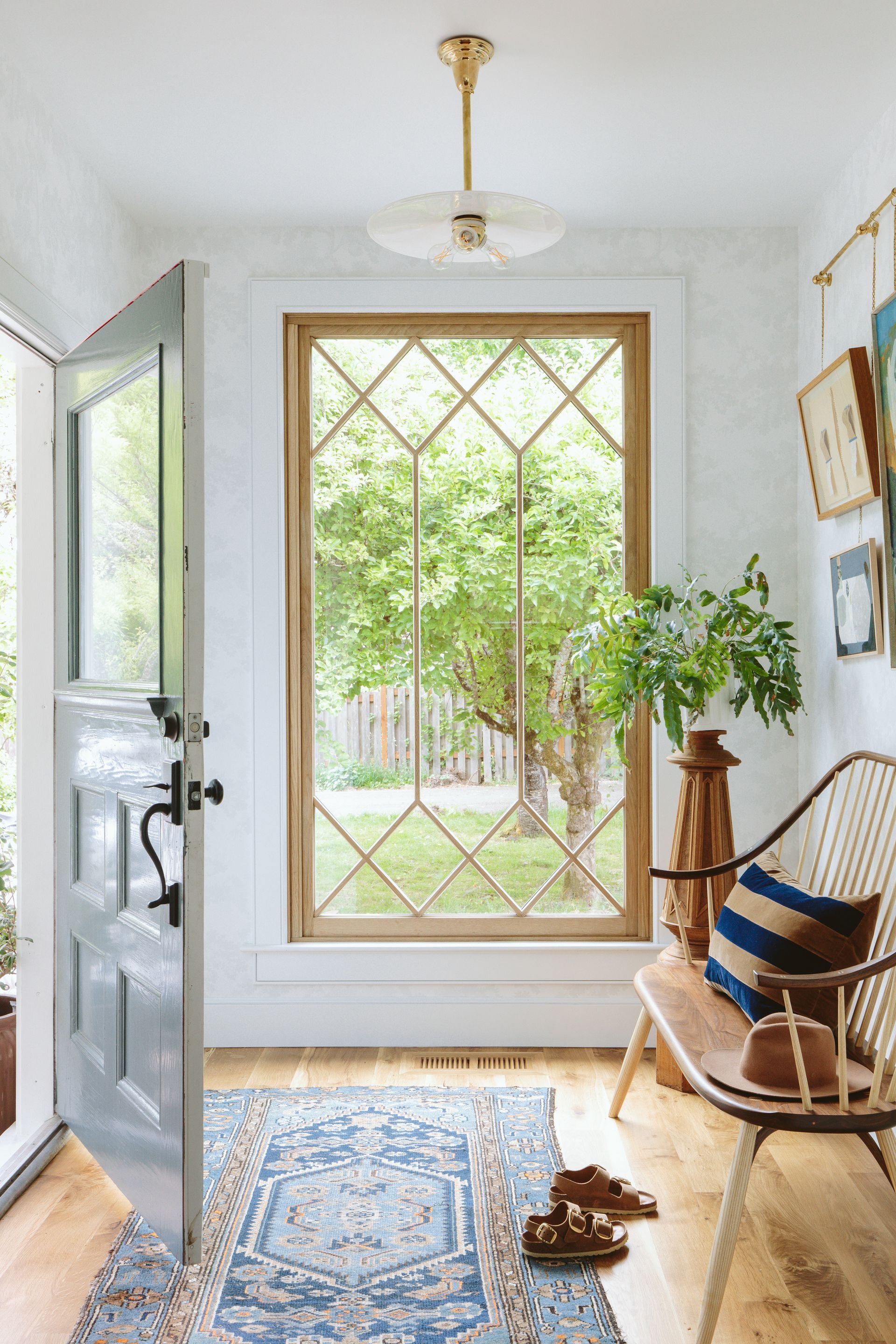 Entry with diamond shaped divided lites in window, a vintage rug, and a Windsor style bench.