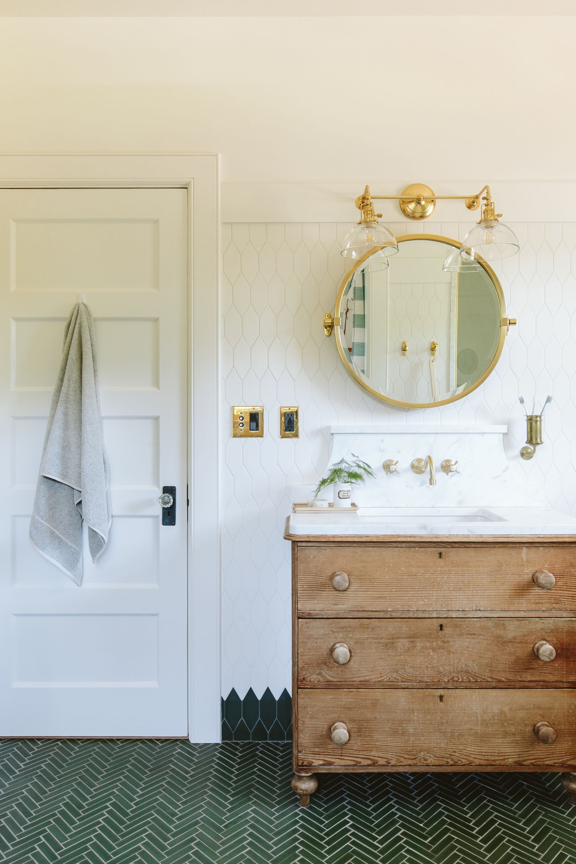The 1910 kids' bathroom remodel with herringbone tile floor, picket- shaped tile base and wall tile, and a vintage dresser turned vanity cabinet.