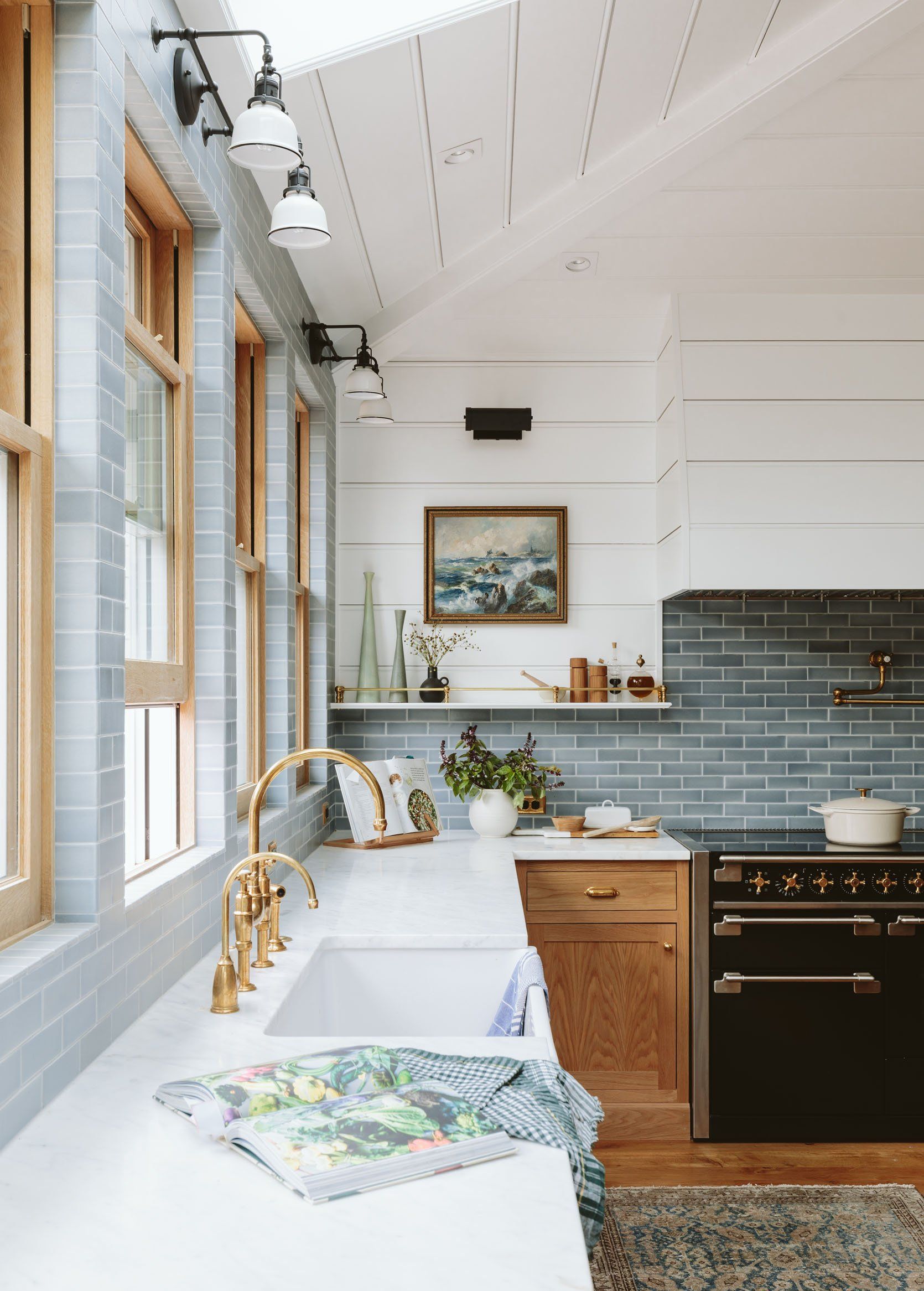 Kitchen with white countertops, gold fixtures, wooden cabinets, black stove, and blue tiled backsplash.