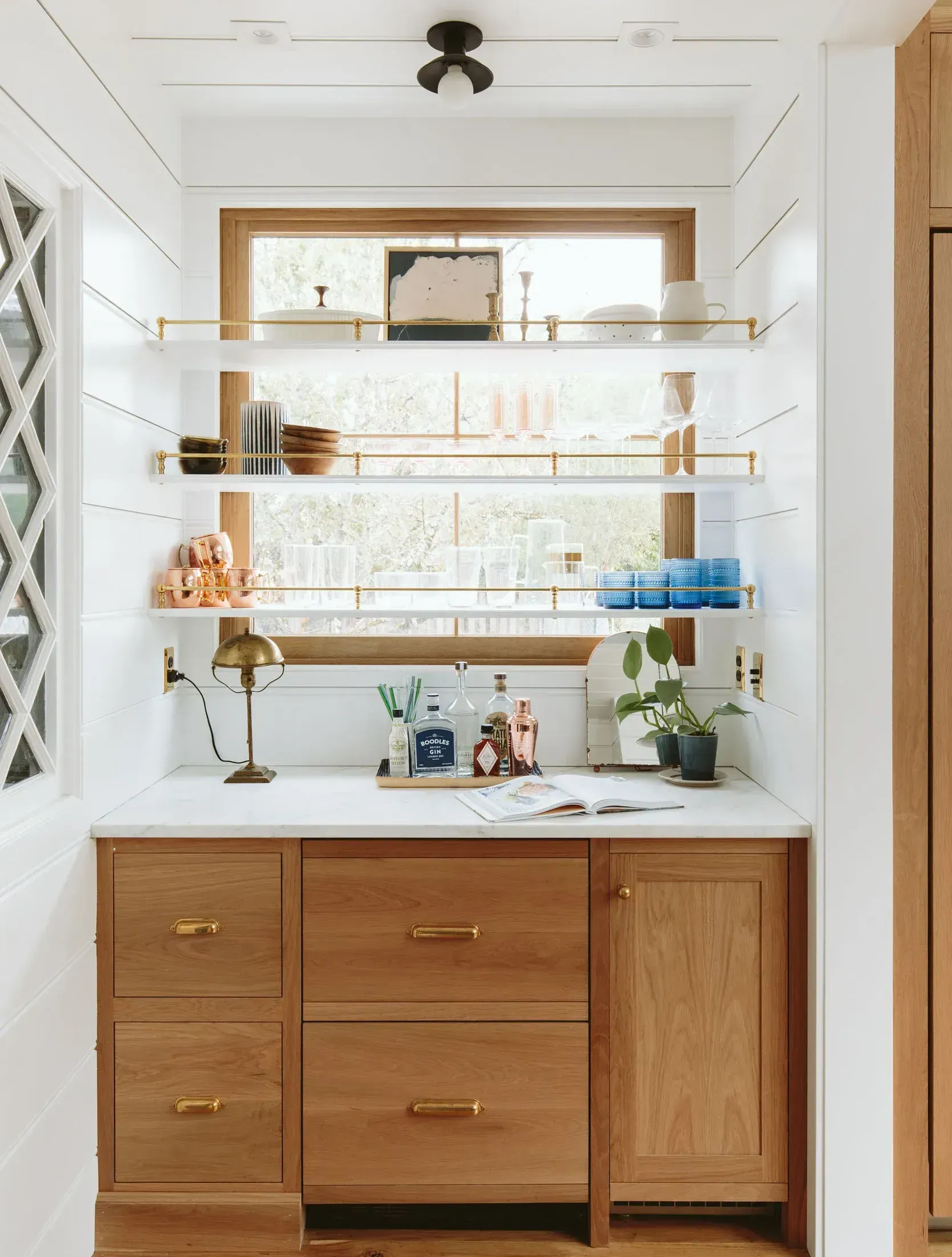Built-in kitchen bar with wooden cabinets, open shelves, and a window.