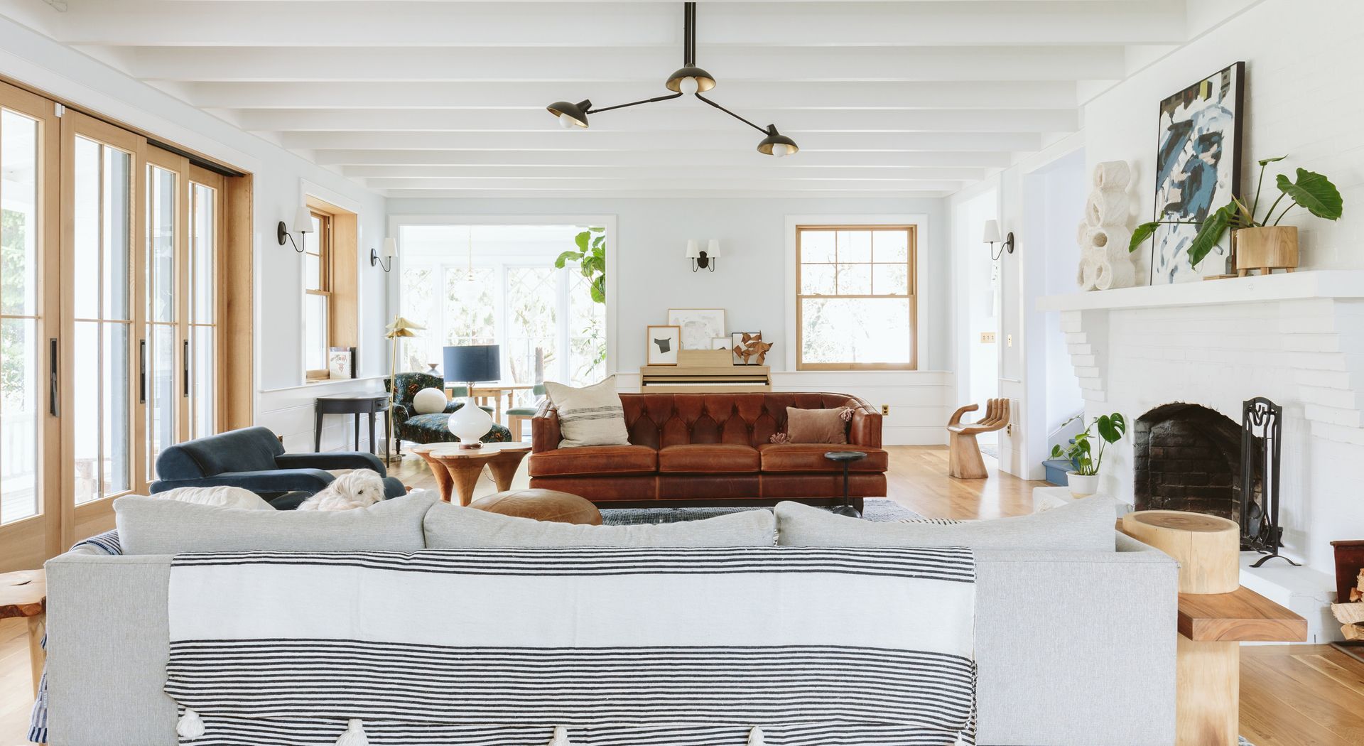 Farmhouse living room with large accordion doors, brick fireplace and eclectic furnishings, fixtures and finishes.