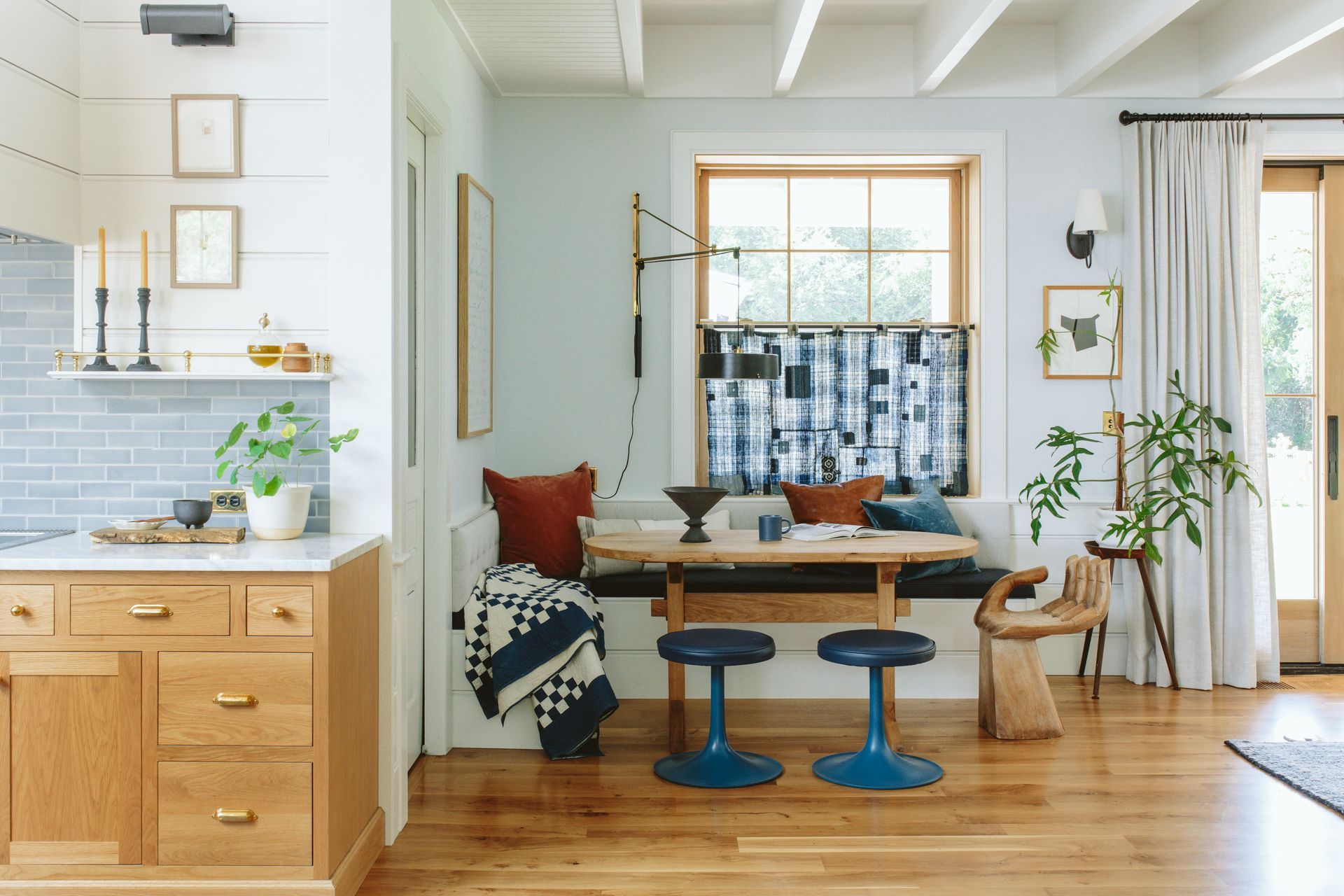 Eating nook with eclectic furnishings, fixtures, and finishes and a bit of the kitchen visible around the corner.