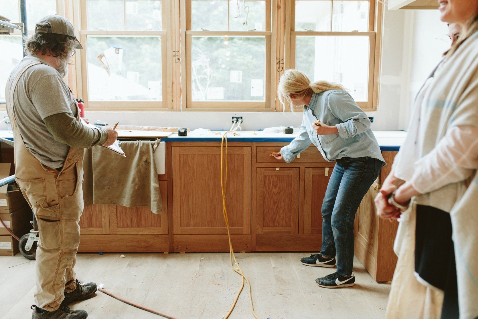 People inspecting new kitchen cabinets in a room under construction.