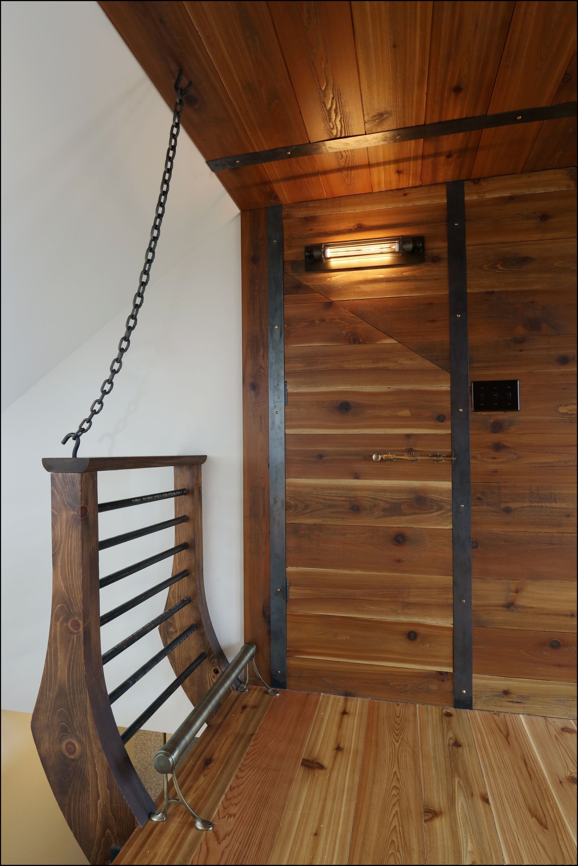 The wood paneling wall finish with metal strapping and the curved wood and metal railing evoke Jules Verne images in the new dormer