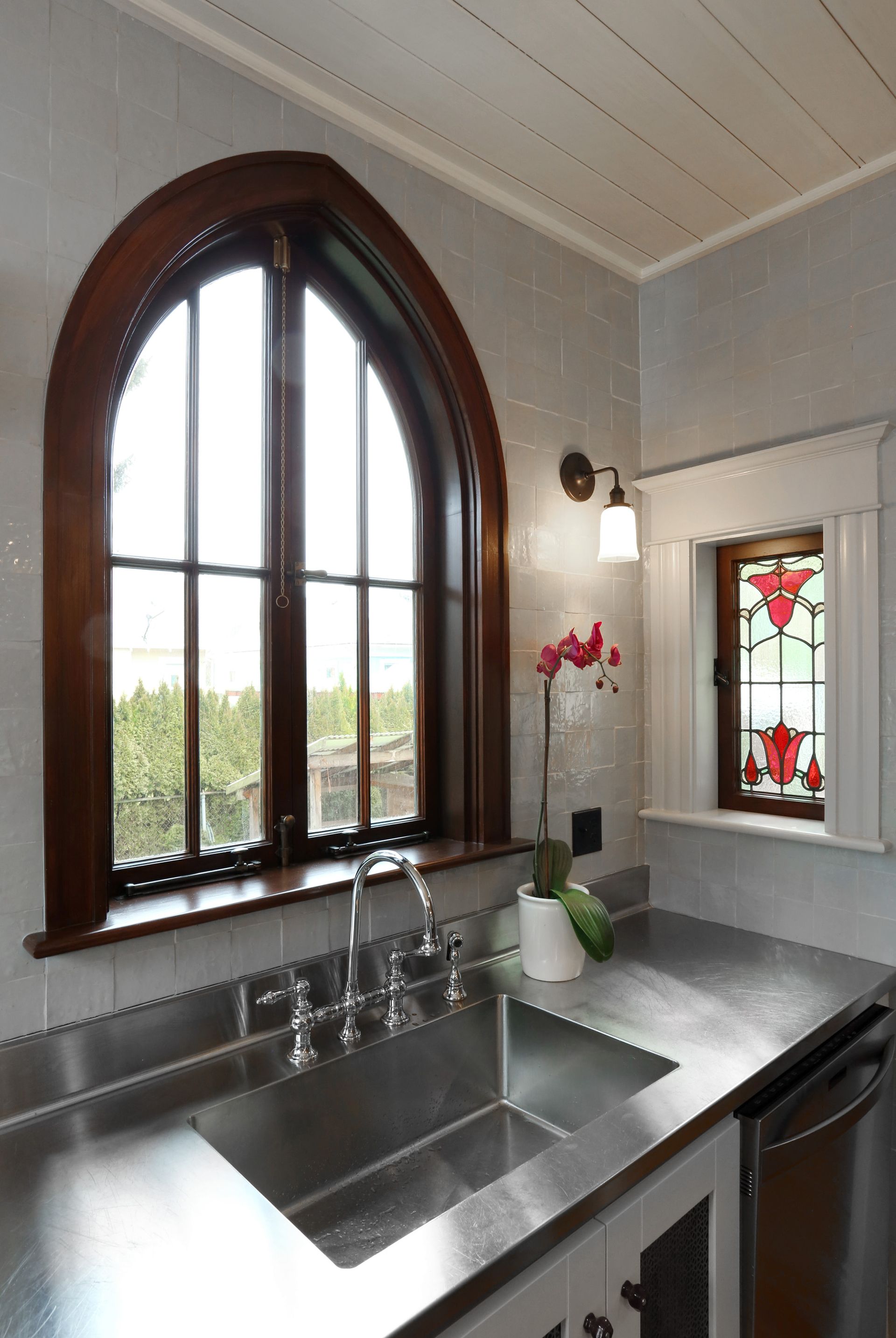 A custom gothic casement window sits above the kitchen sink and opens to the backyard