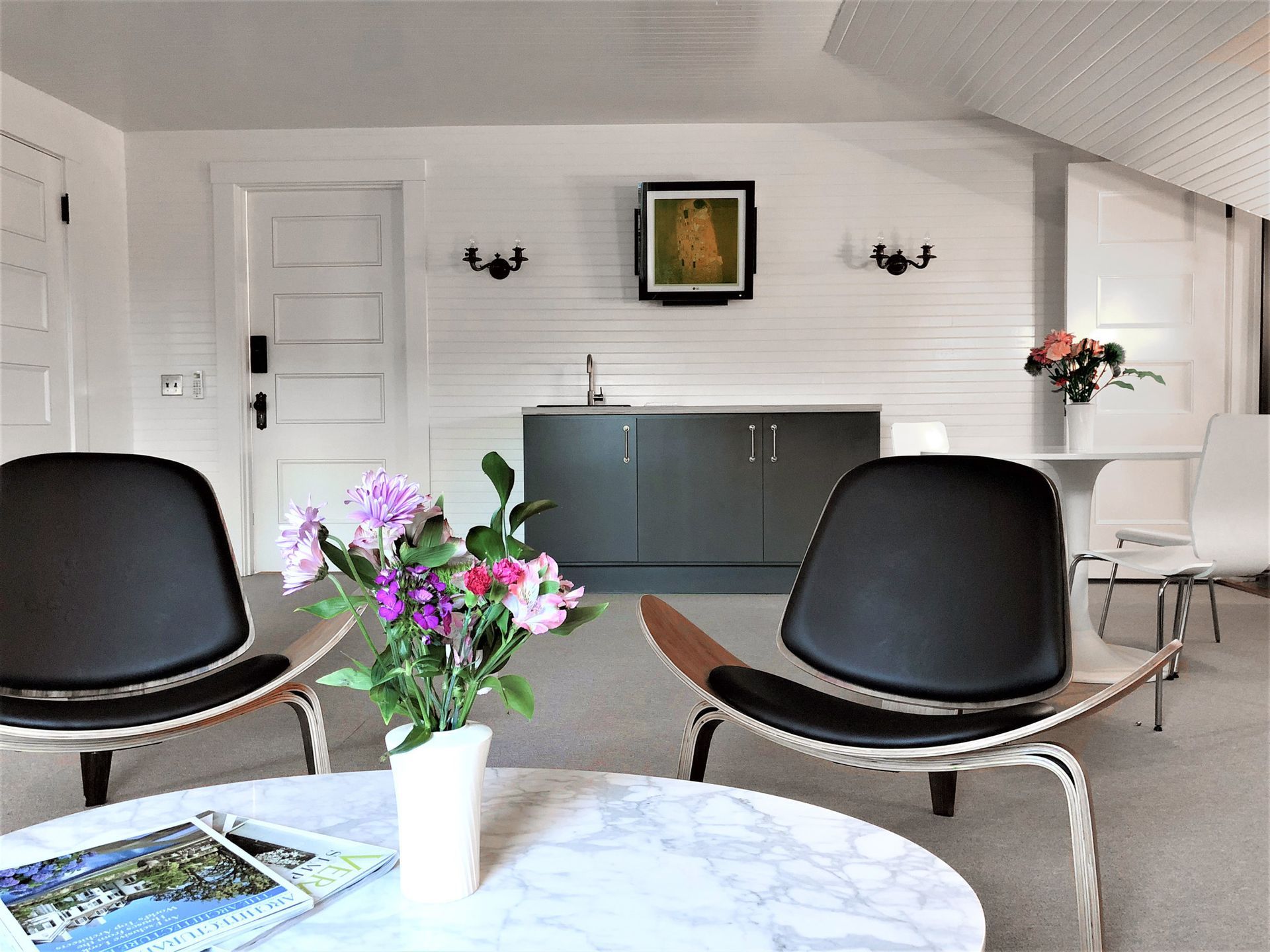 A living room with two chairs and a table with a vase of flowers on it