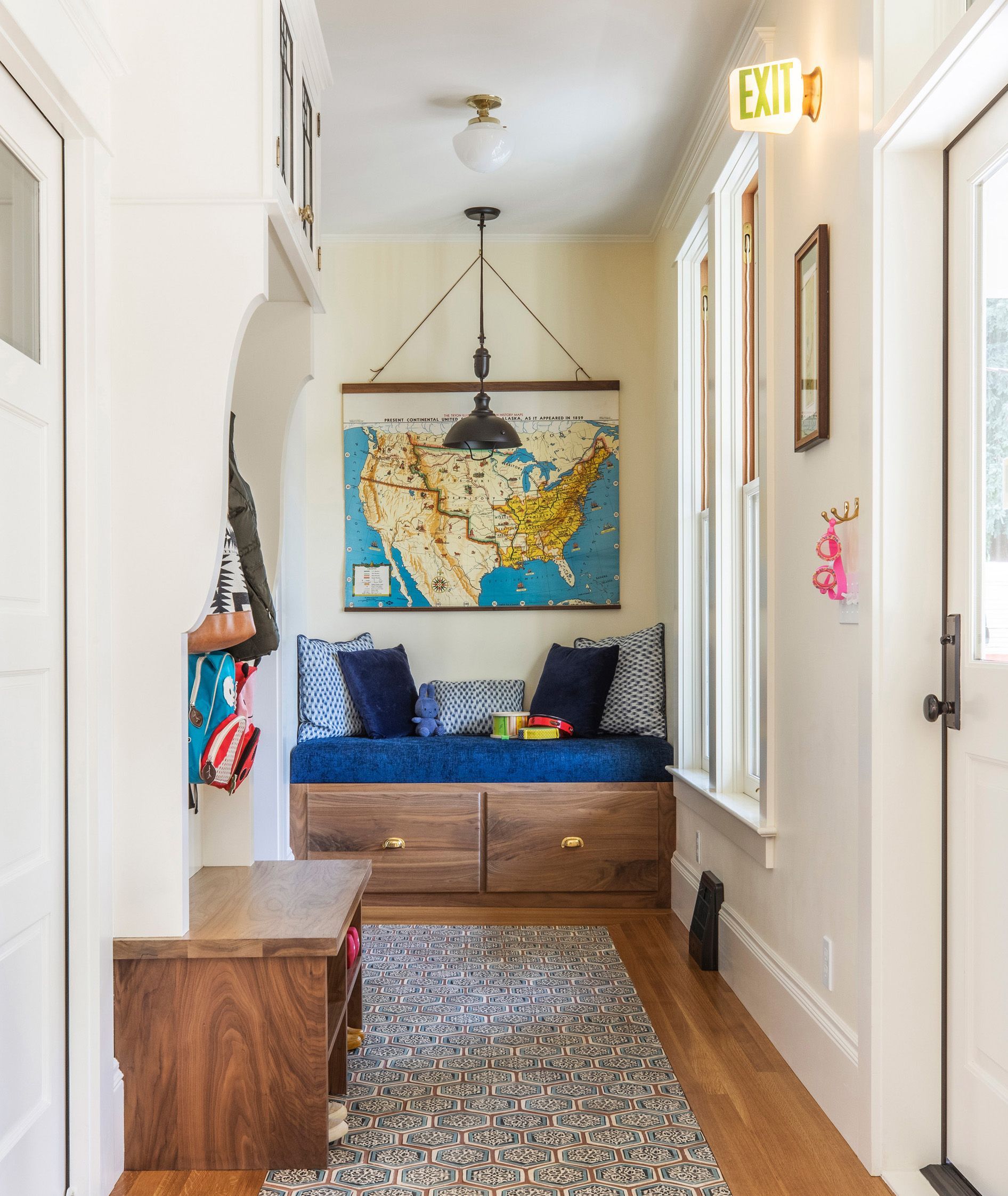 Flooded with light, this respite from the elements is cheerful and practical, with a hand-painted tile carpet and a custom padded bench. A pendant over the bench seating, flush-mount ceiling lights, and a vintage exit sign by the door, add visual interest as well as options for lighting according to use.