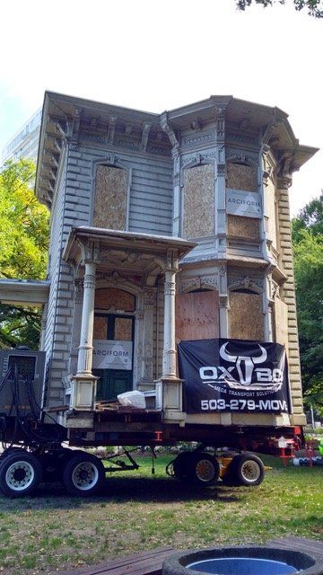 A large house is being moved by a truck.