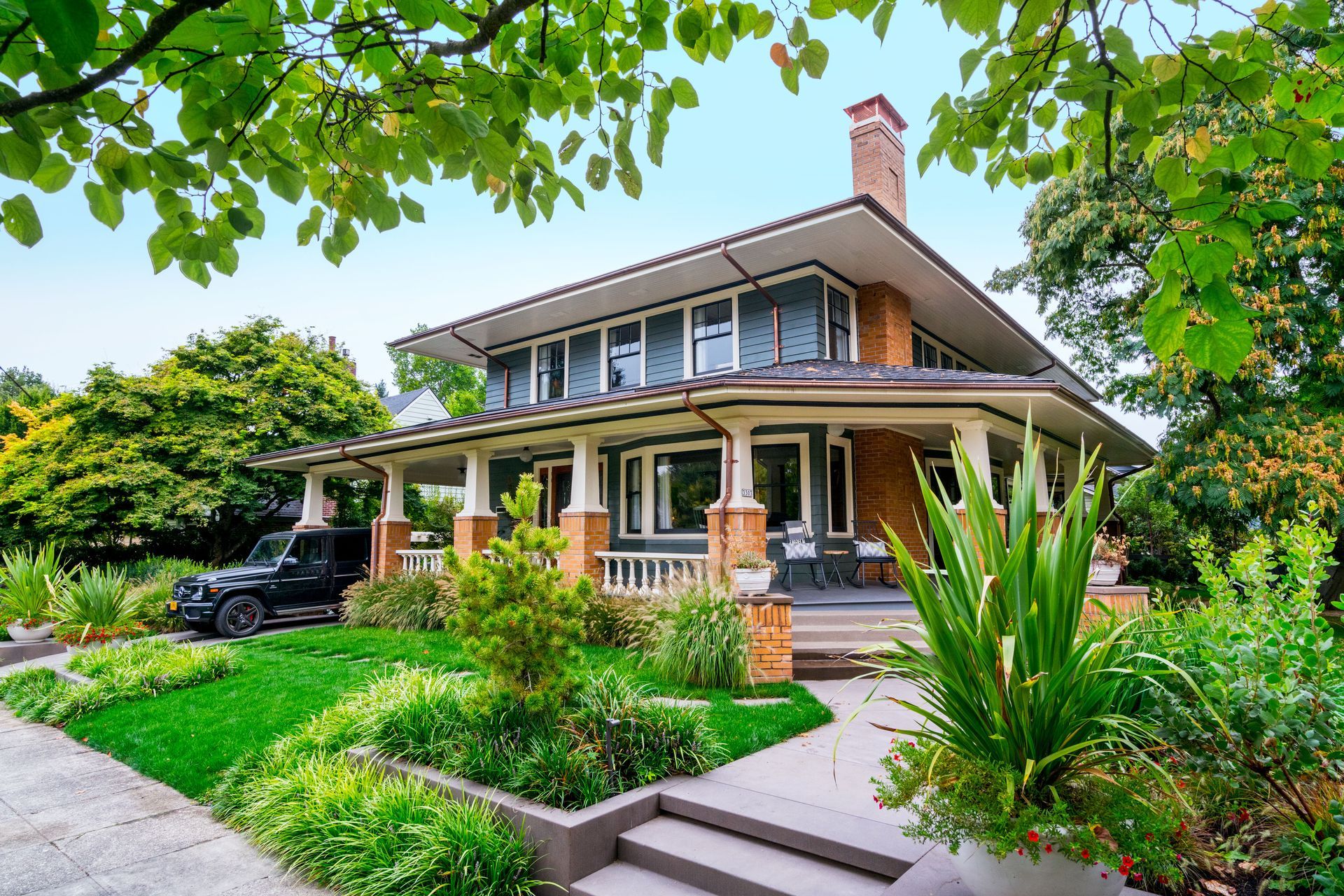Street view of a 1915 prairie-style craftsman home with landscaped yard.