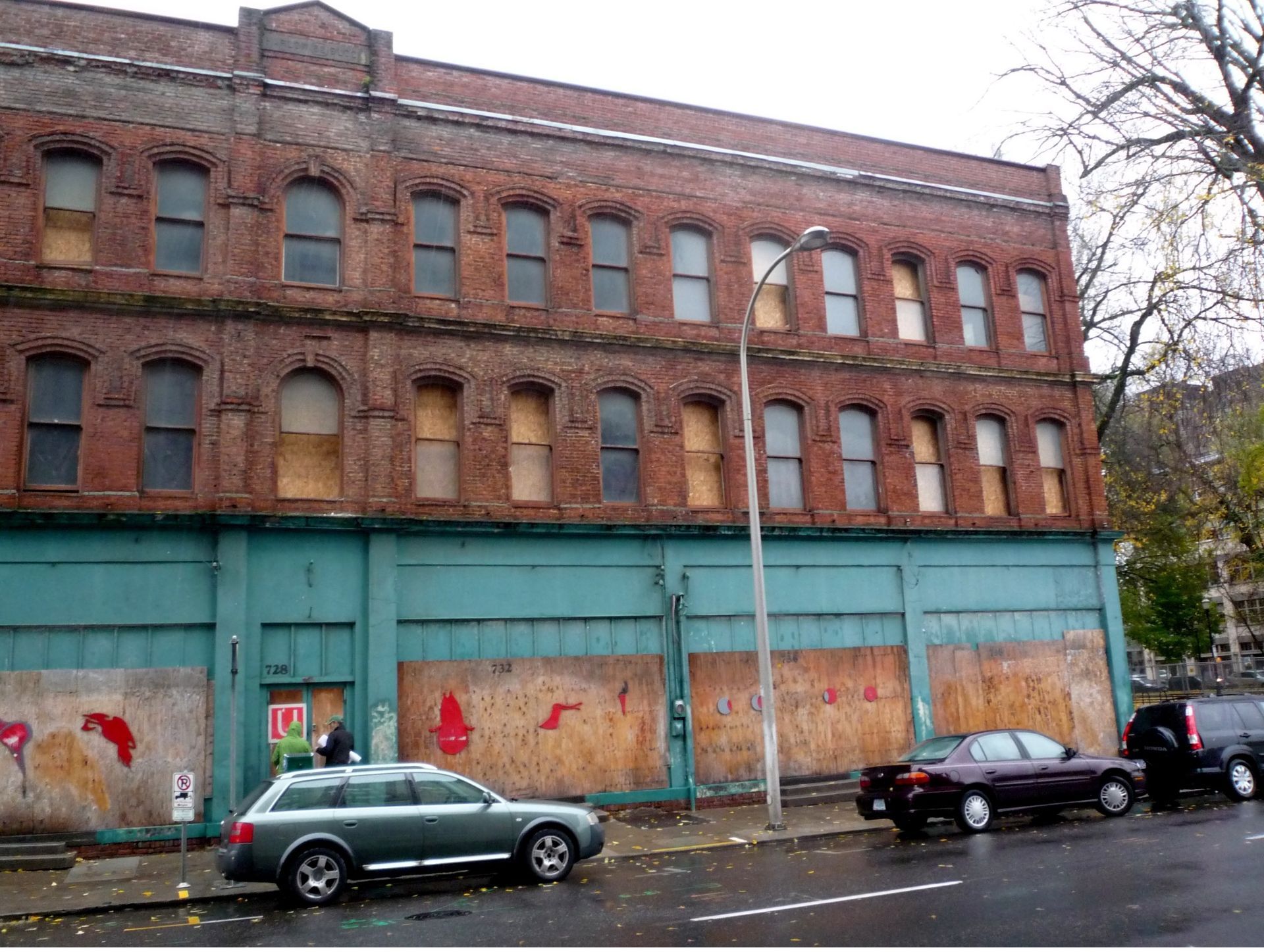A green suv is parked in front of a large brick building
