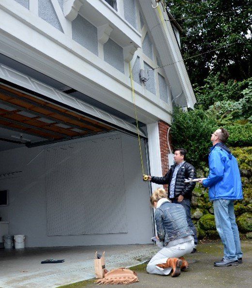 A group of people measuring a garage door with a tape measure