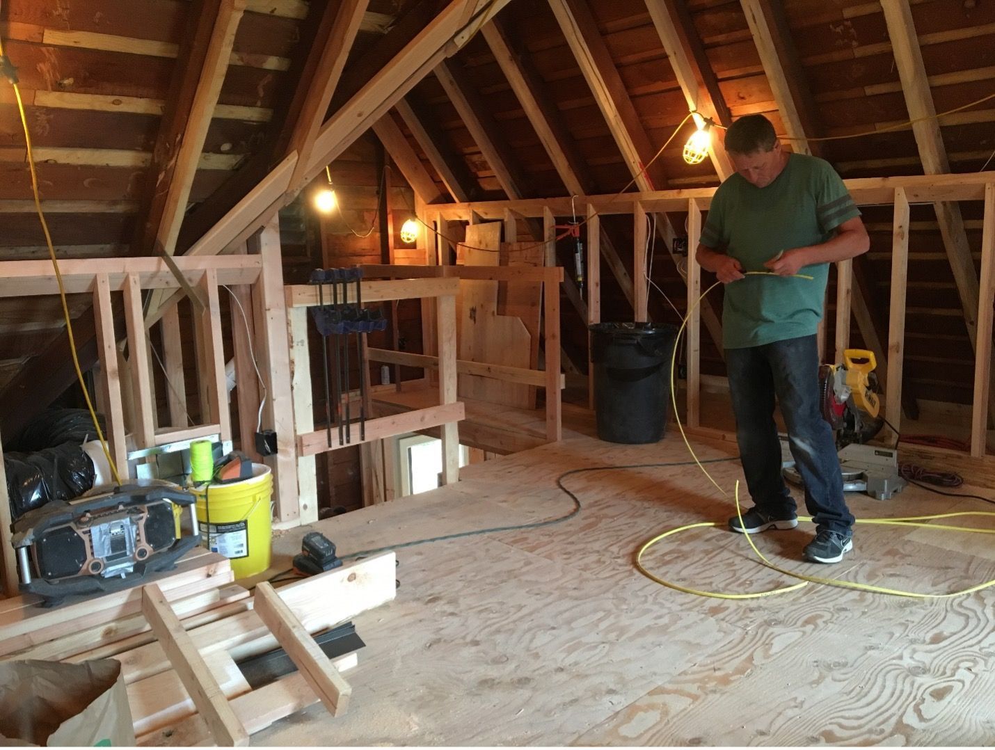 A man in a green shirt is working in an attic.