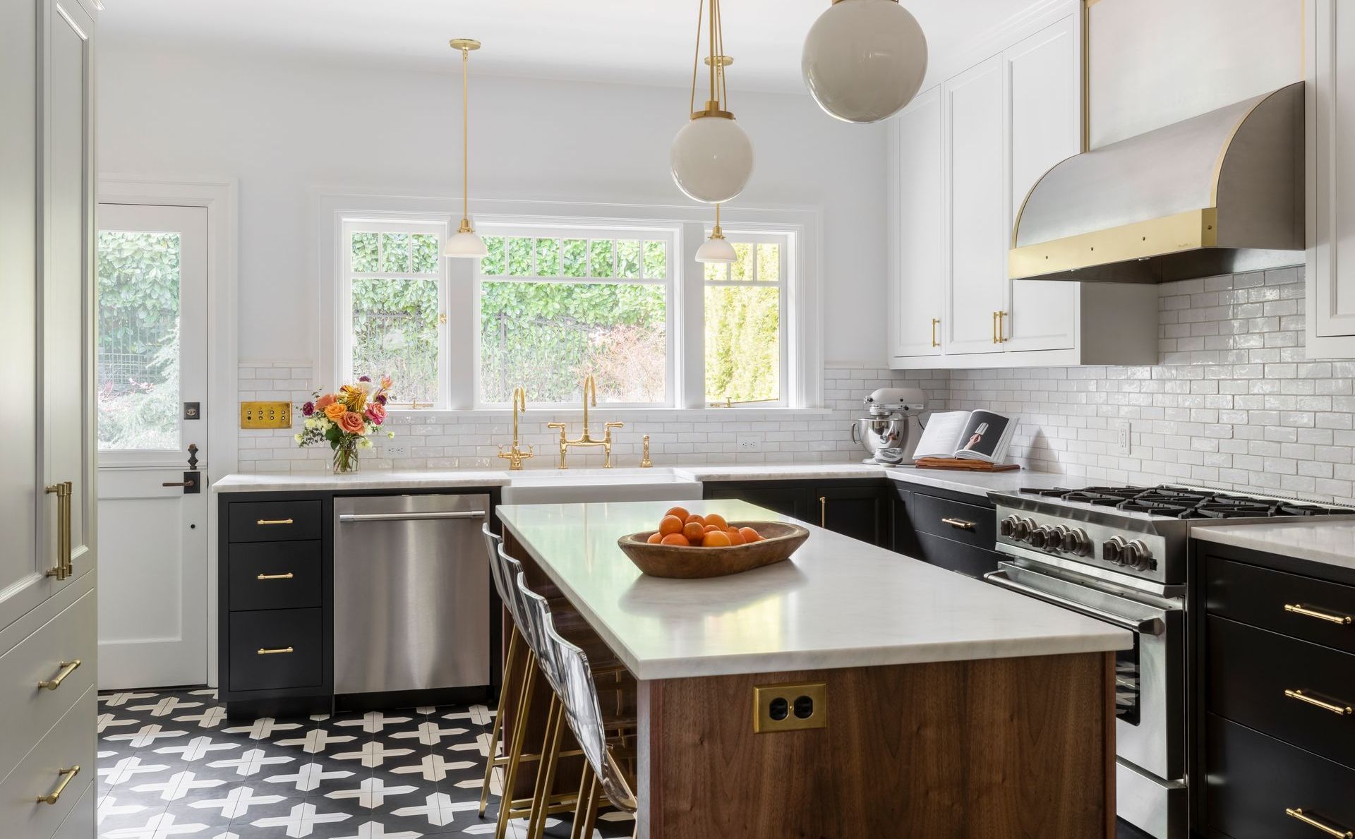View of the sink wall with backyard view in this black and white kitchen.