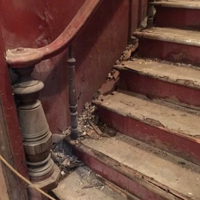 An old wooden staircase with a wooden railing and steps.