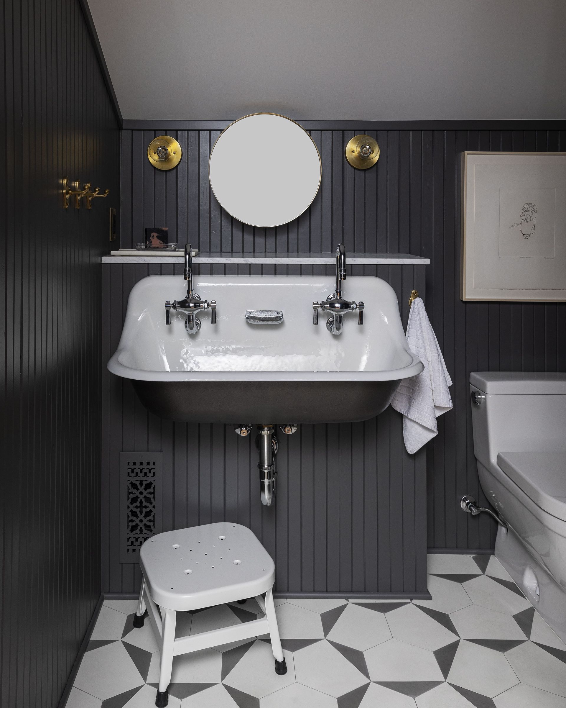 An attic WC below a sloped ceiling with an enamel utility sink, concrete hex floor tile and v-groove wall paneling.