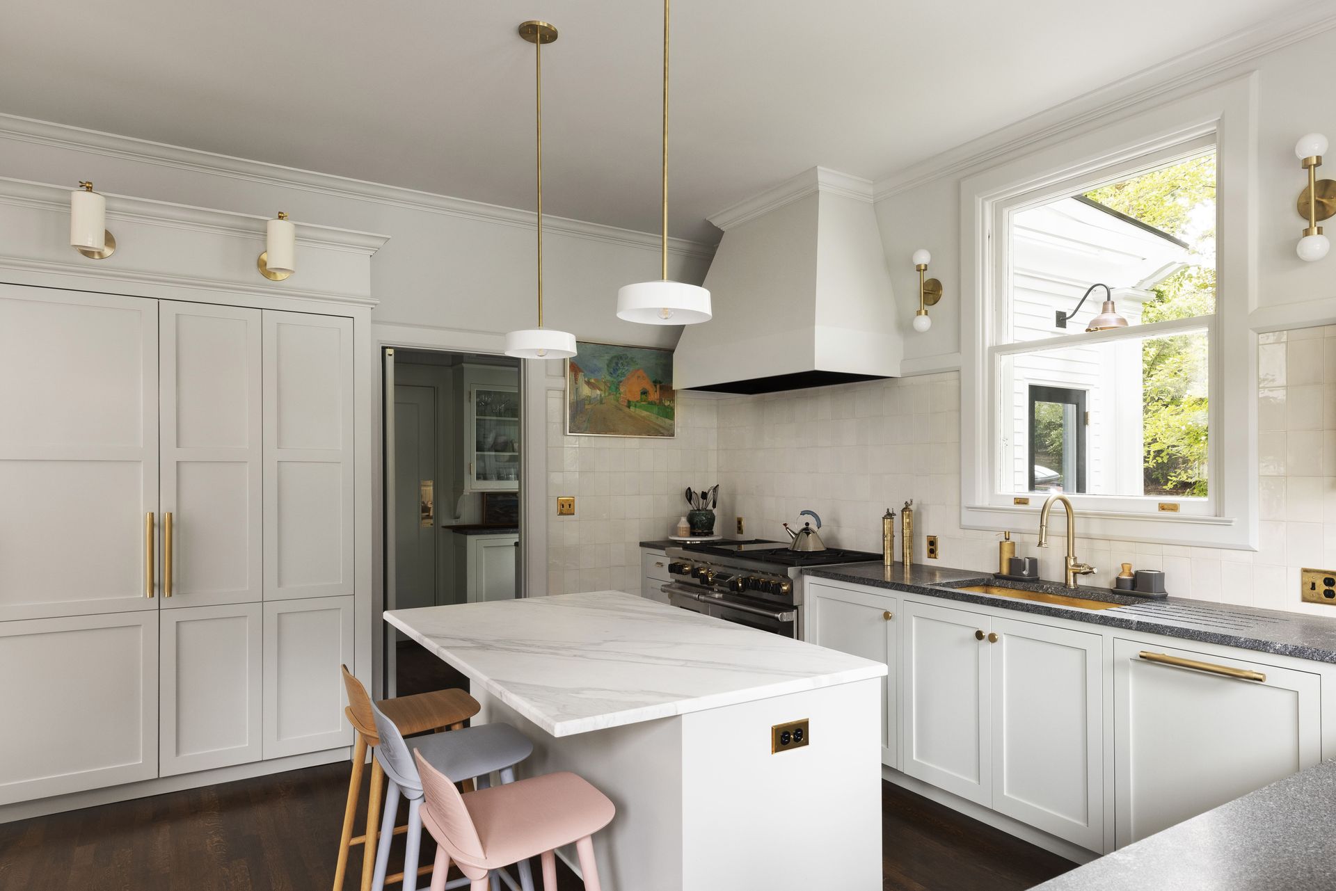 A remodeled colonial kitchen with custom cabinetry, Danish stools at the island and contemporary art and fixtures.