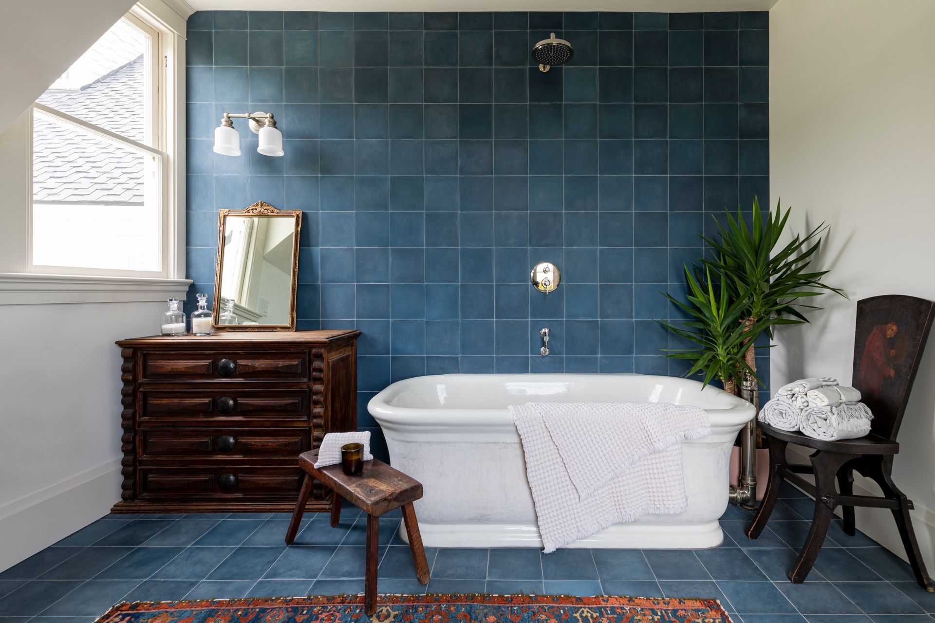 In the adjacent bathroom, moody blue tile sets off the freestanding bathtub.