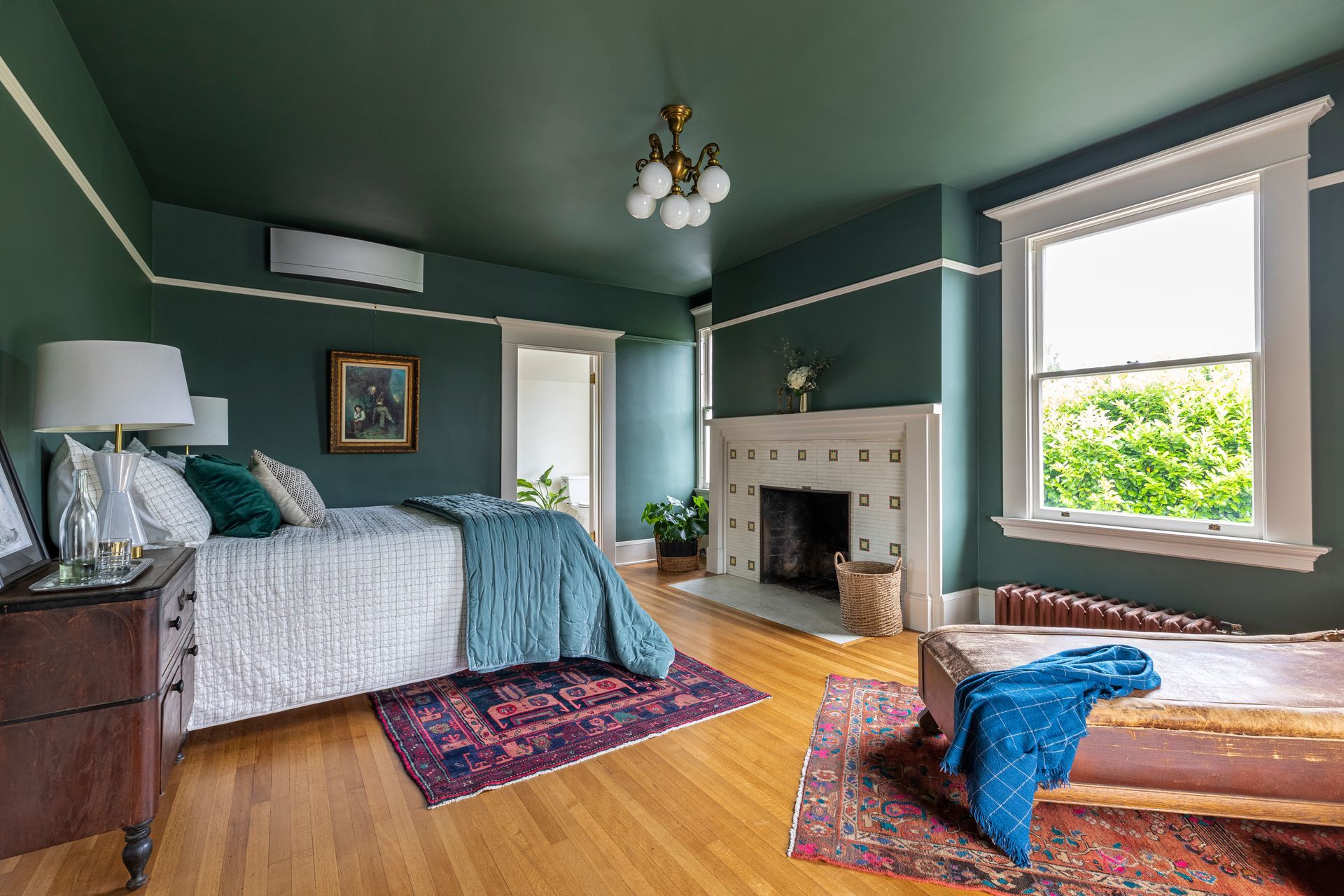 A deep-hued bedroom with a fireplace is a cozy place for guests.