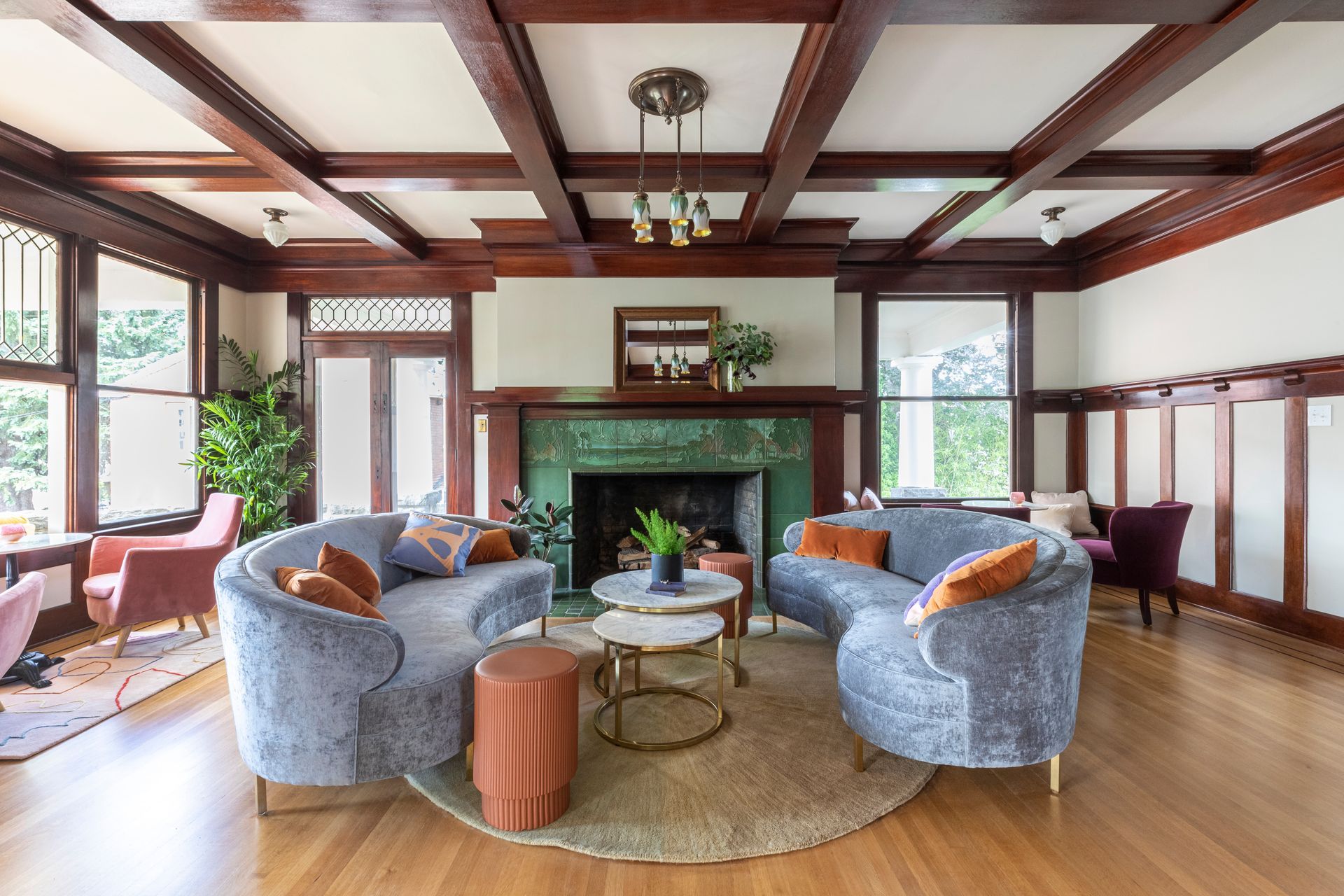 Another original fireplace in a sitting room with box beams in rich stained wood.