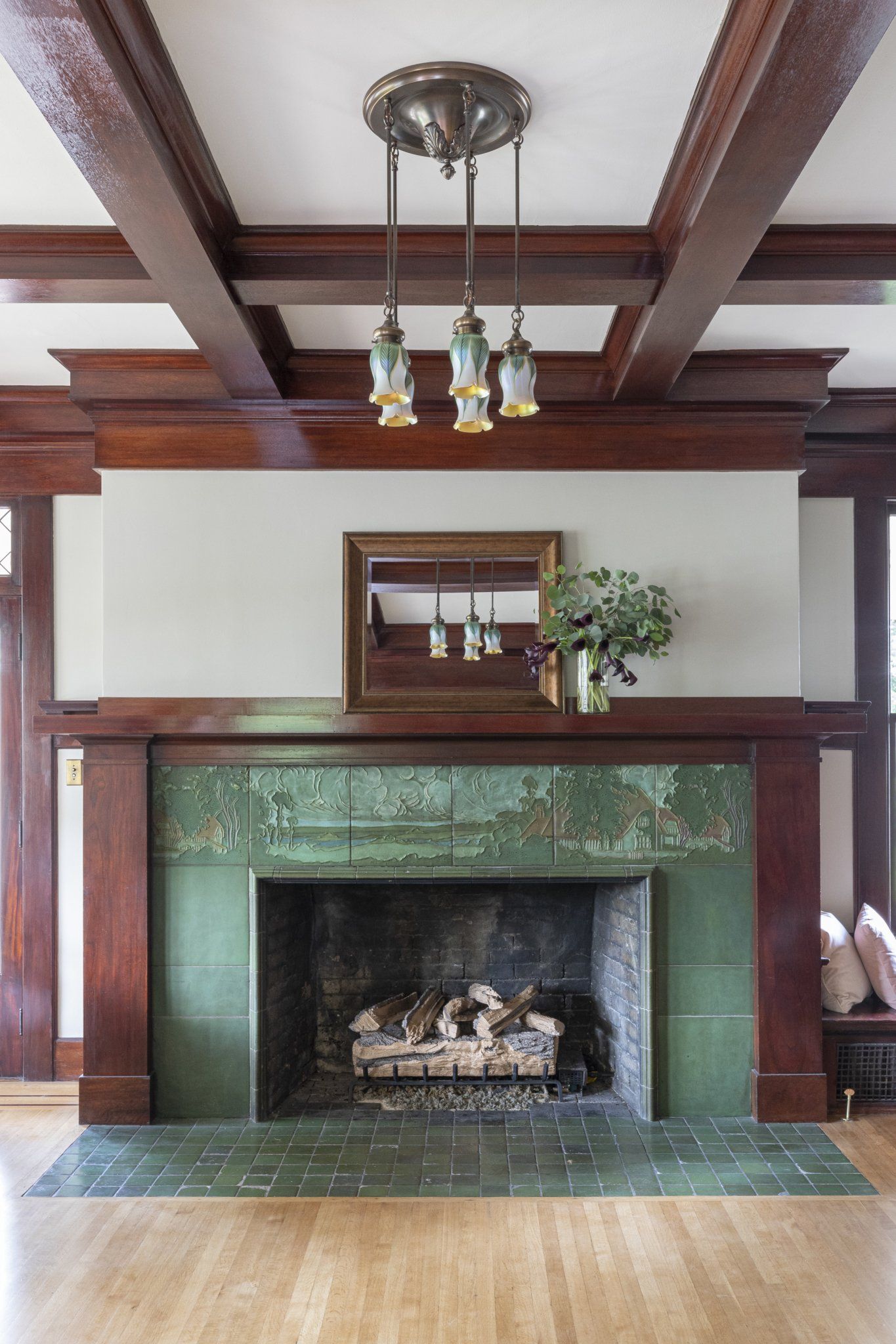 A fireplace with a green tile mantle in a living room.
