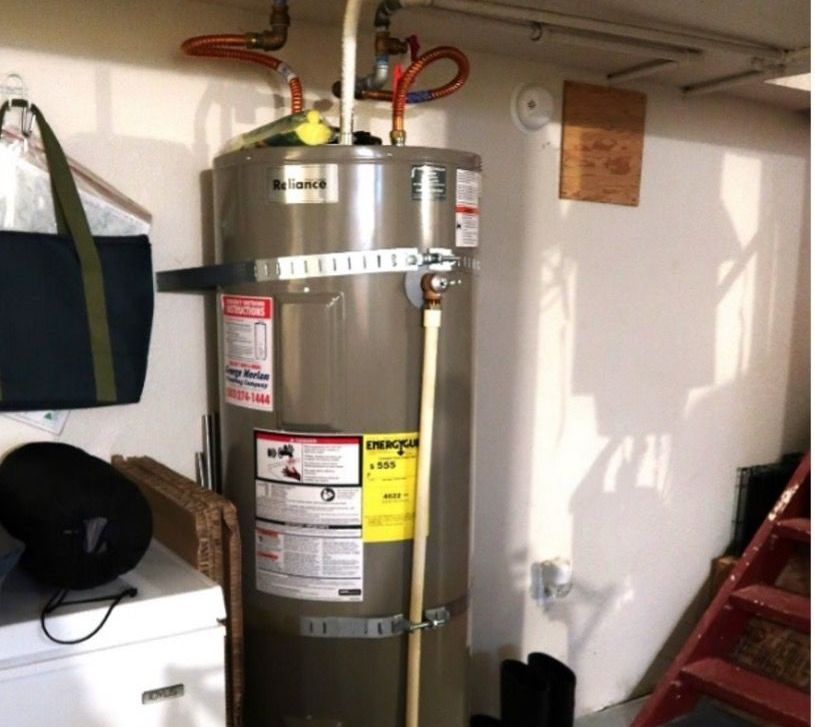 A gray water heater with a yellow warning label